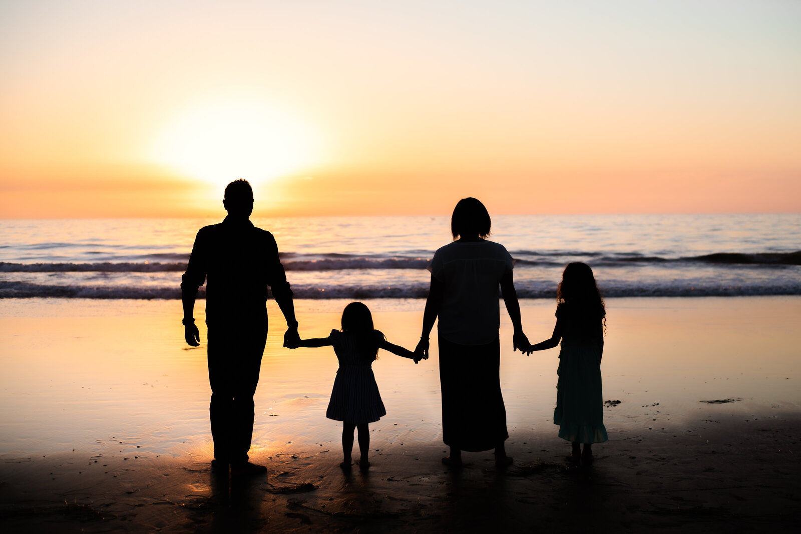 Family Photographer, the silhouette of a family walking on the beach