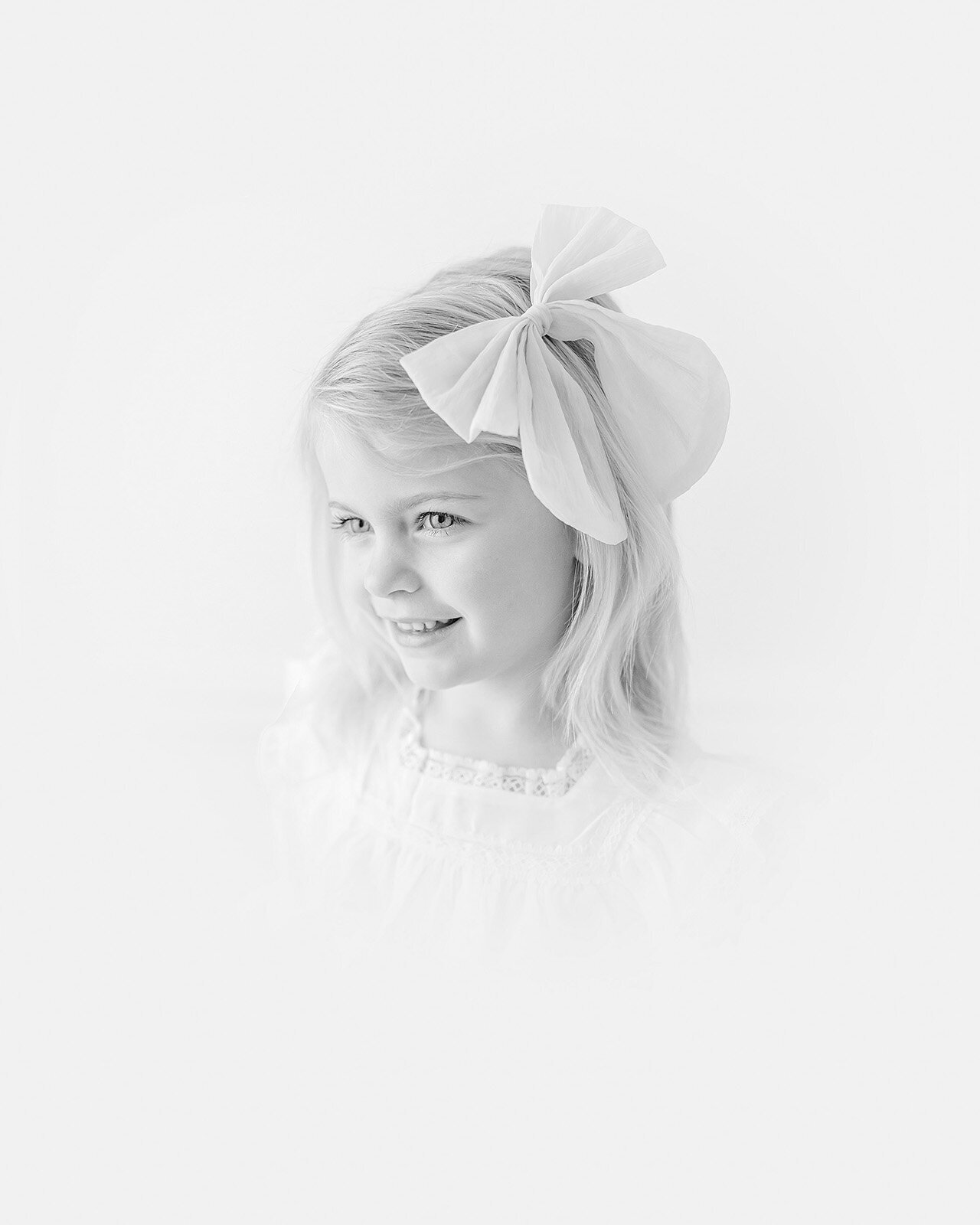 In a charming portrait of childhood, a young child with light brown hair and a white Peter Pan collar shirt glances to the side, embodying the essence of timeless children photography against a soft background.