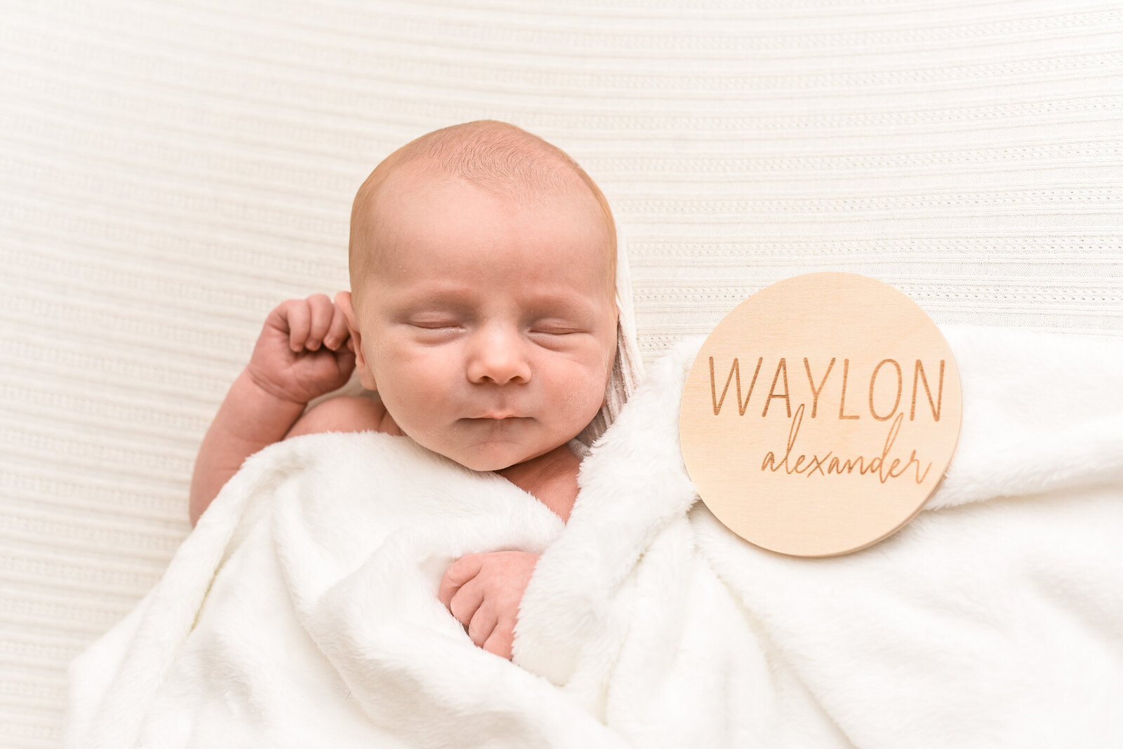 newborn baby laying on stomach with white blanket