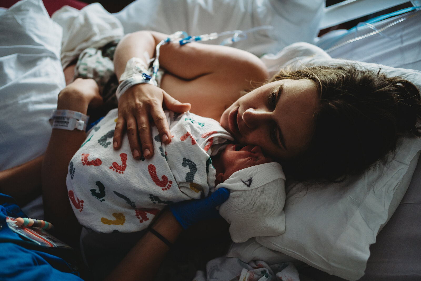 Mom holding newborn after birth while sibling comes to meet her
