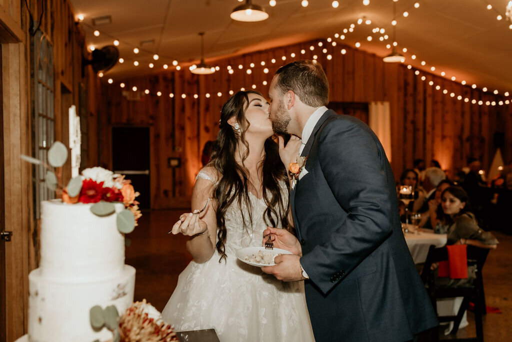 Couple kissing at cake cutting during all-inclusive wedding package