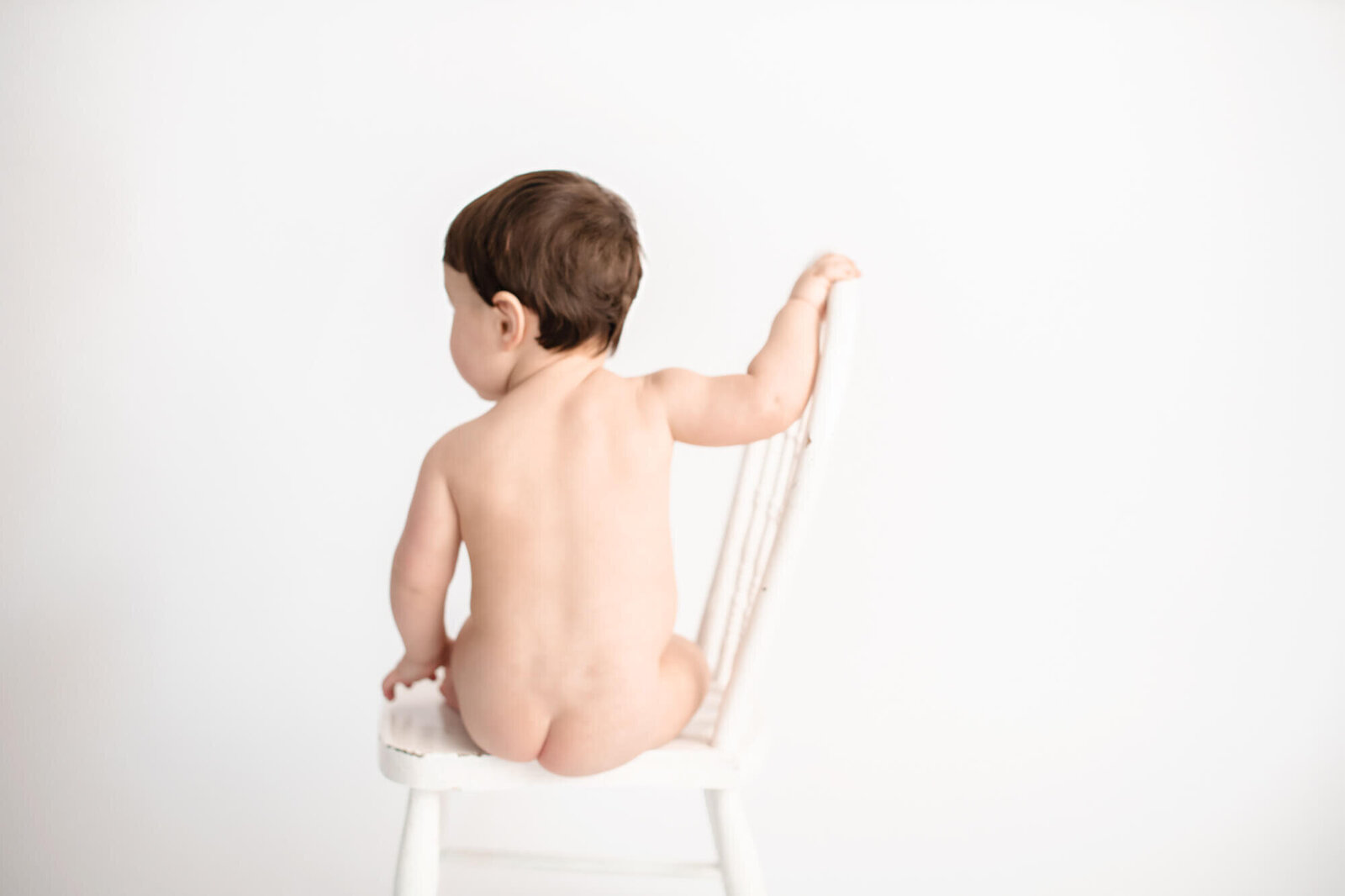 Baby boy in white background sitting on chair