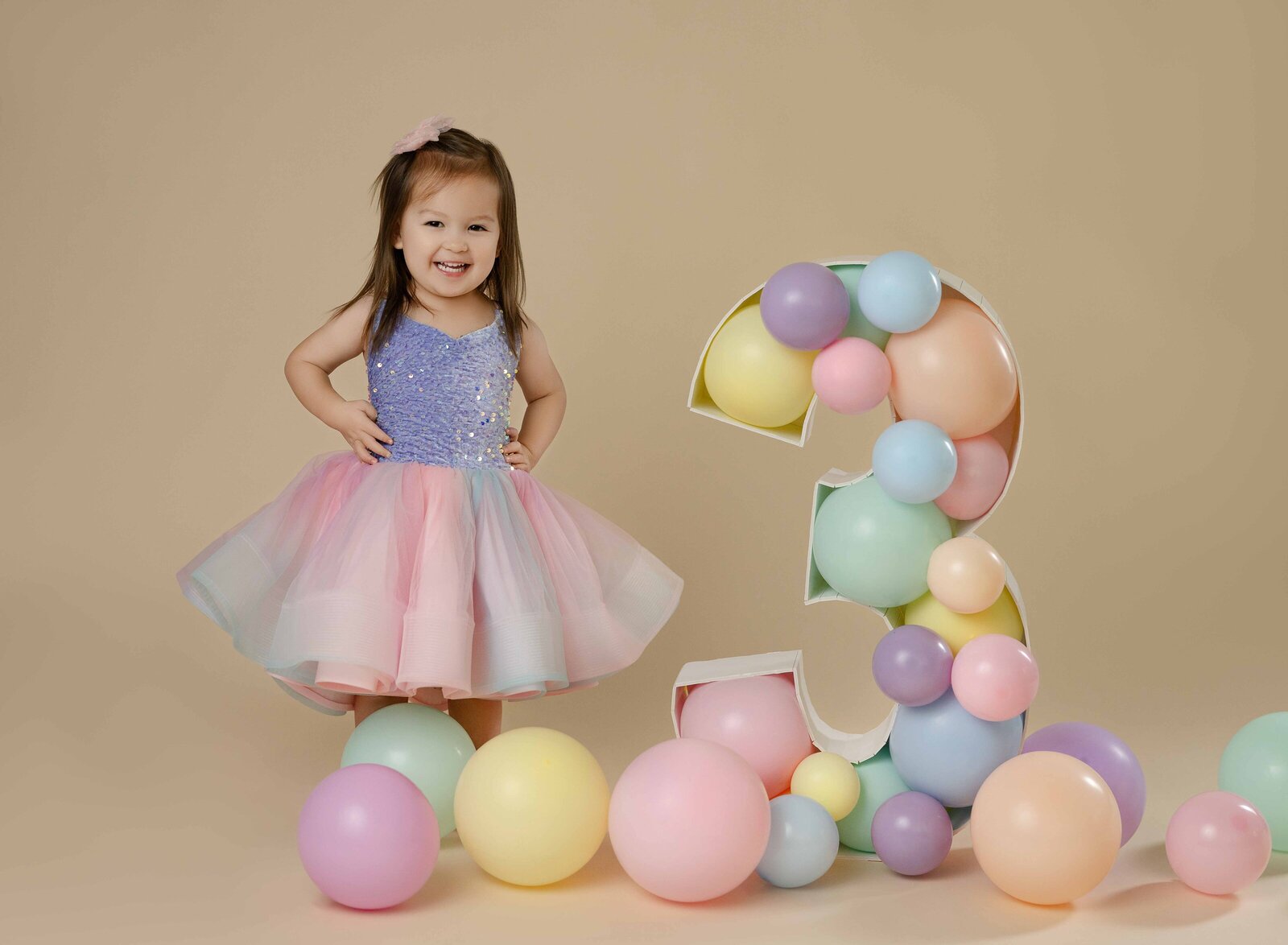 3 year old girl in pastel tulle dress with hands on hip and smiling at the camera. Photographed by Atlanta Birthday Photographer at her Woodstock photo studio.