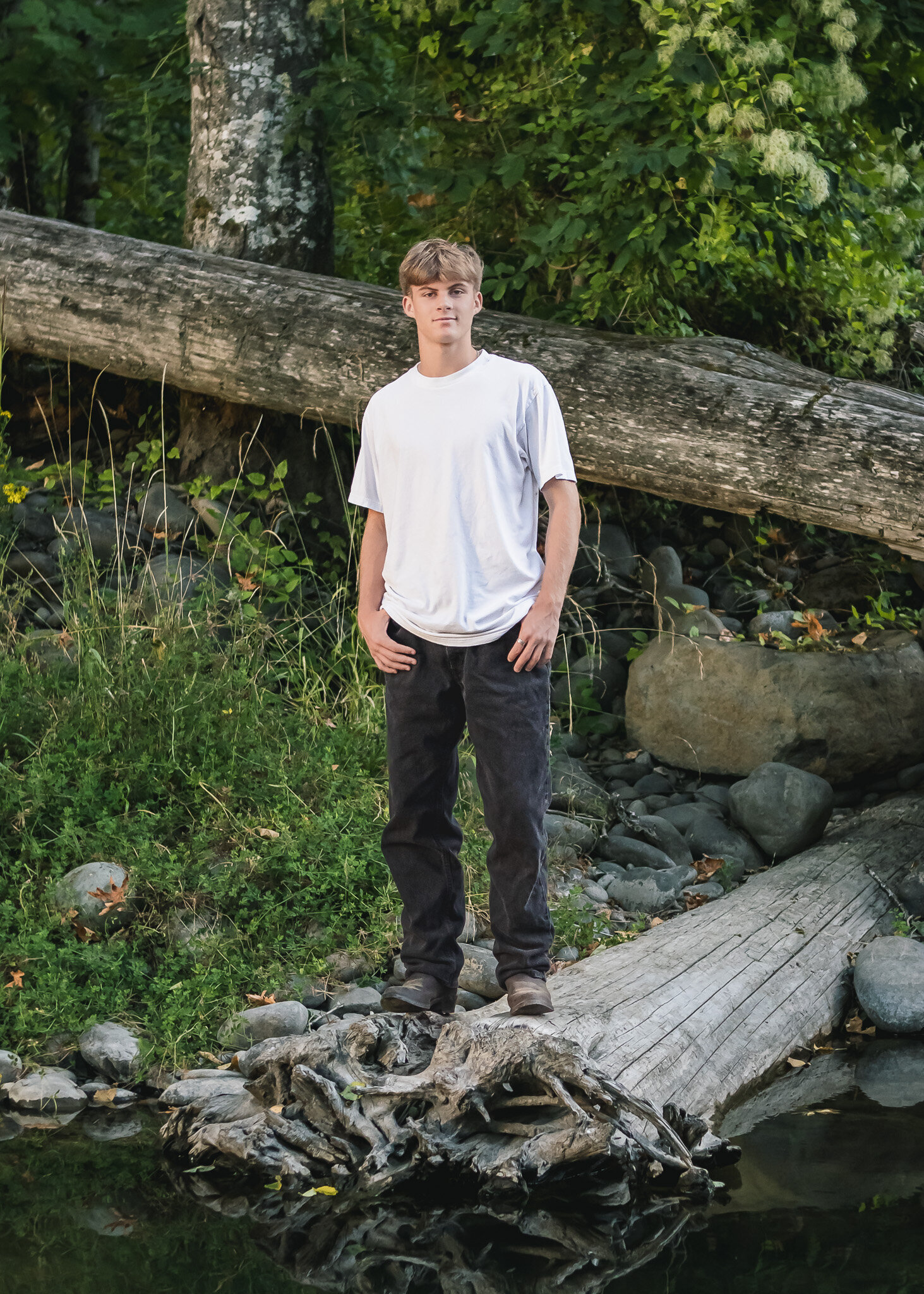 High School senior boy standing on a log near water in Milo Mciver Park, Estacada