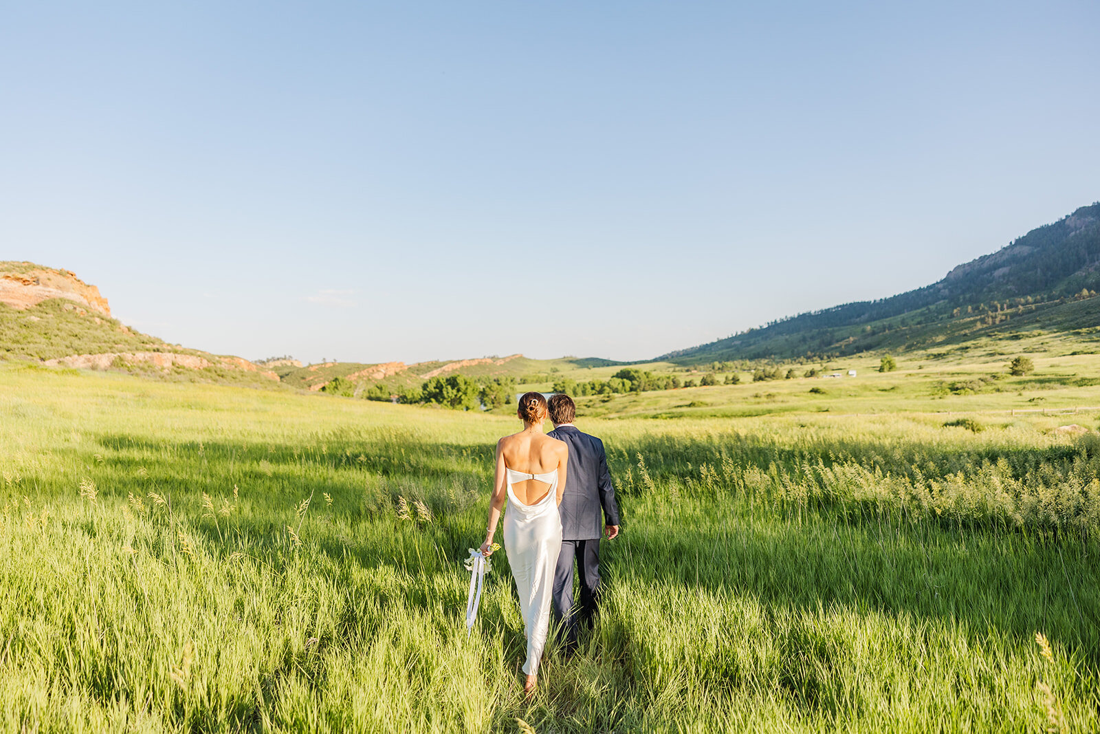 Bride and groom holding hands walking through the tall grass during their elopement at Lory State Park in Ft. Collins, Colorado.