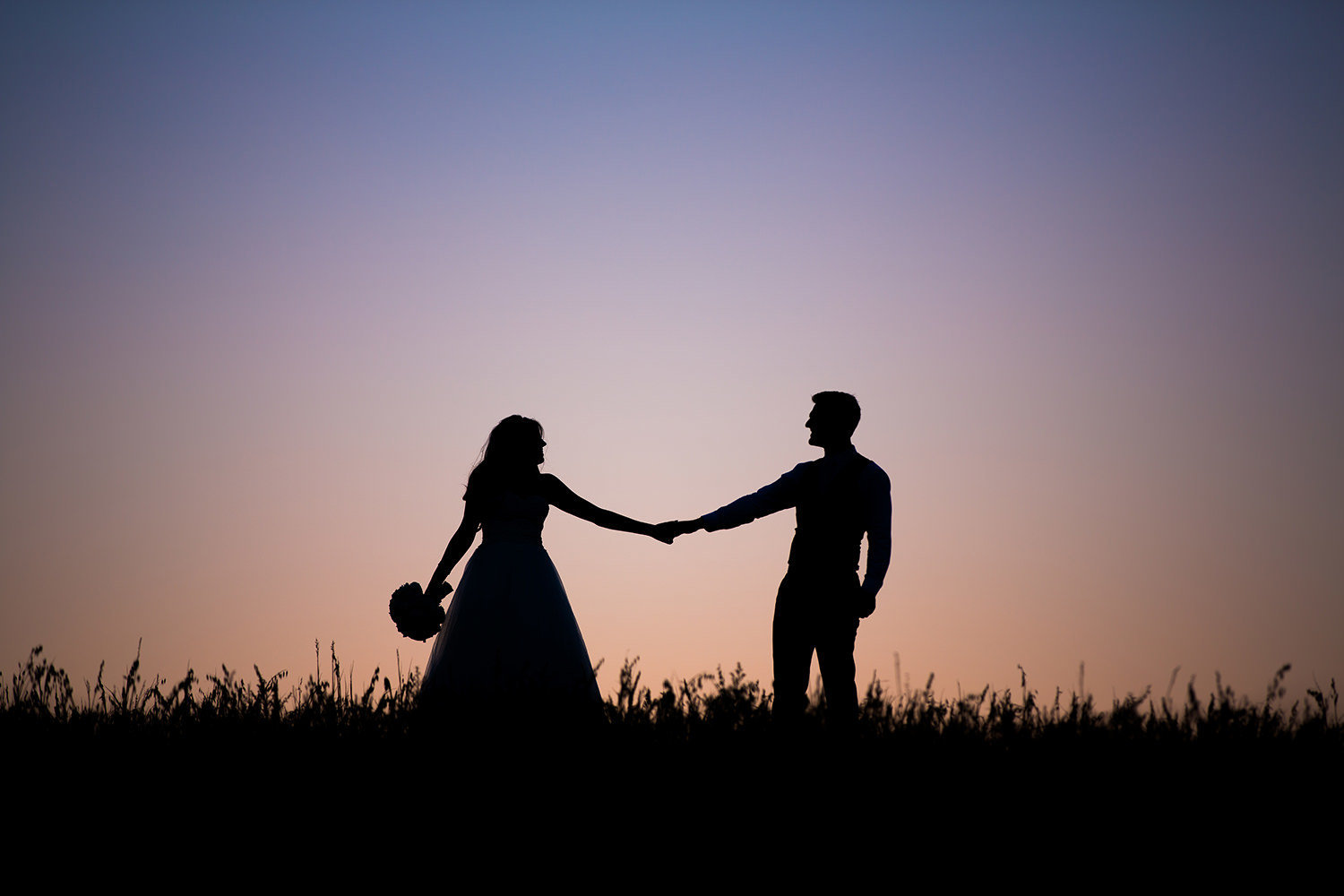 bride and groom holding hands at sunset