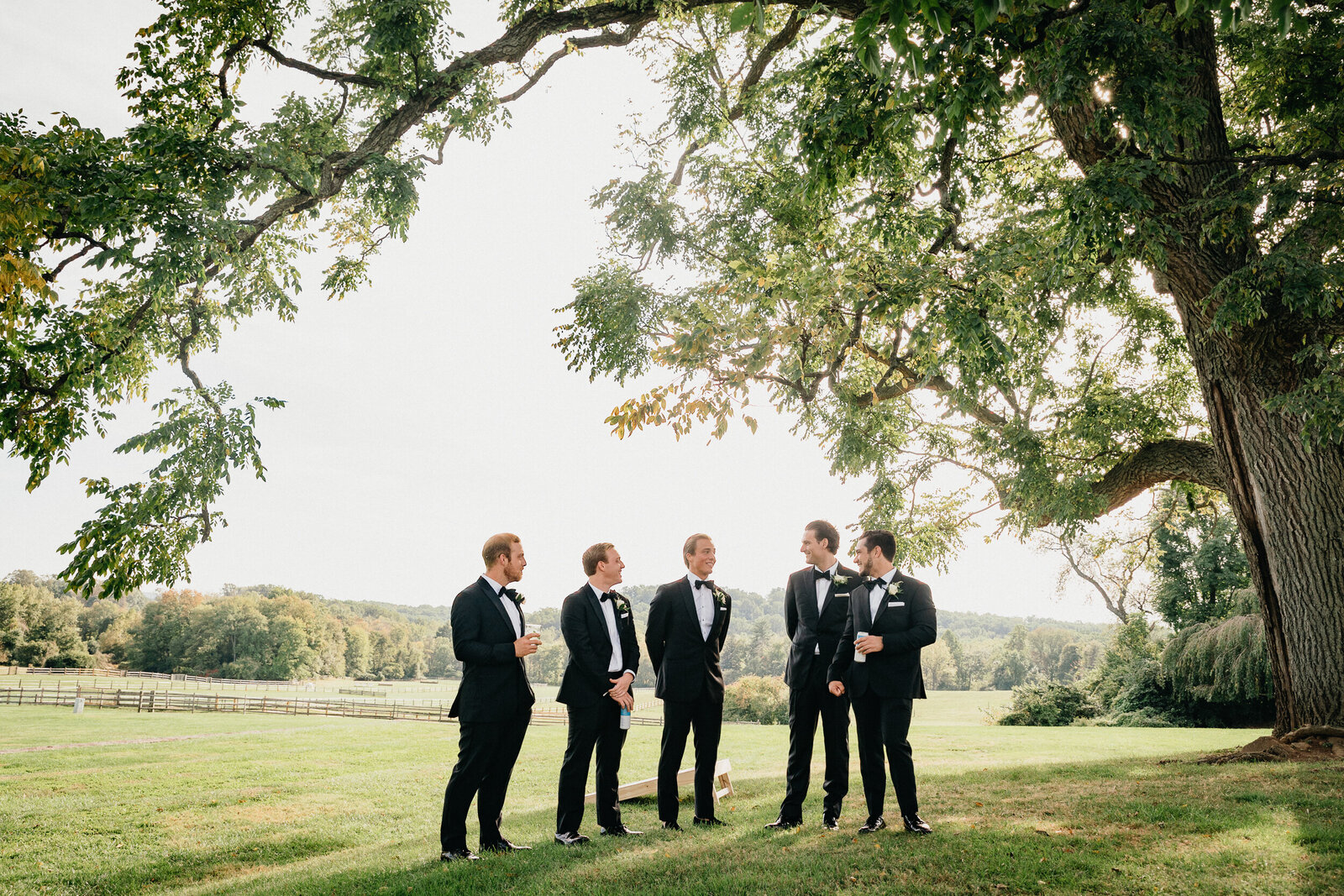 Groomsmen sharing a laugh before the Radnor Hunt wedding ceremony, captured by a Philadelphia wedding photographer.