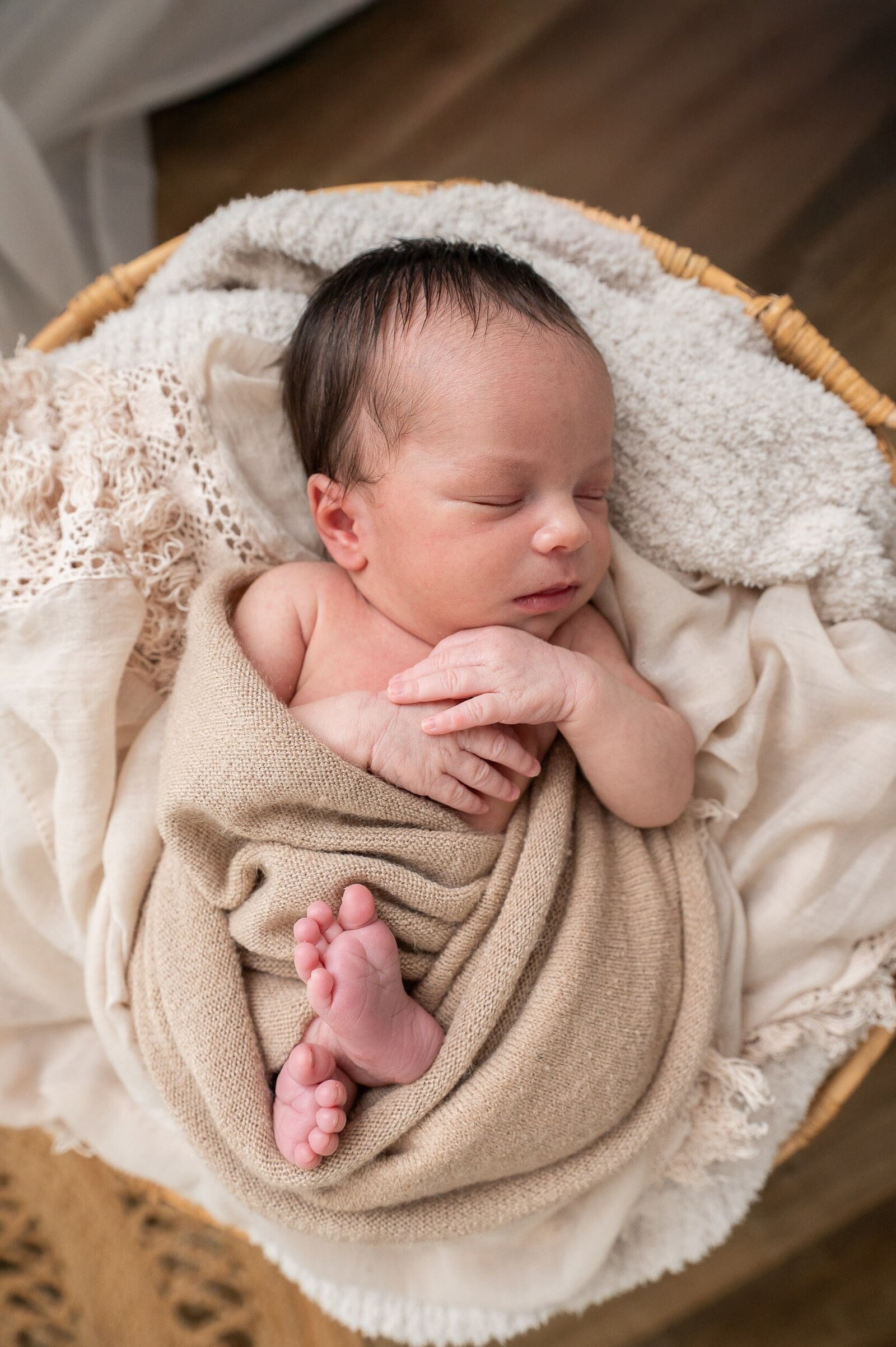 Natural light lifestyle session with a newborn baby swaddled and resting peacefully in a loving home.

