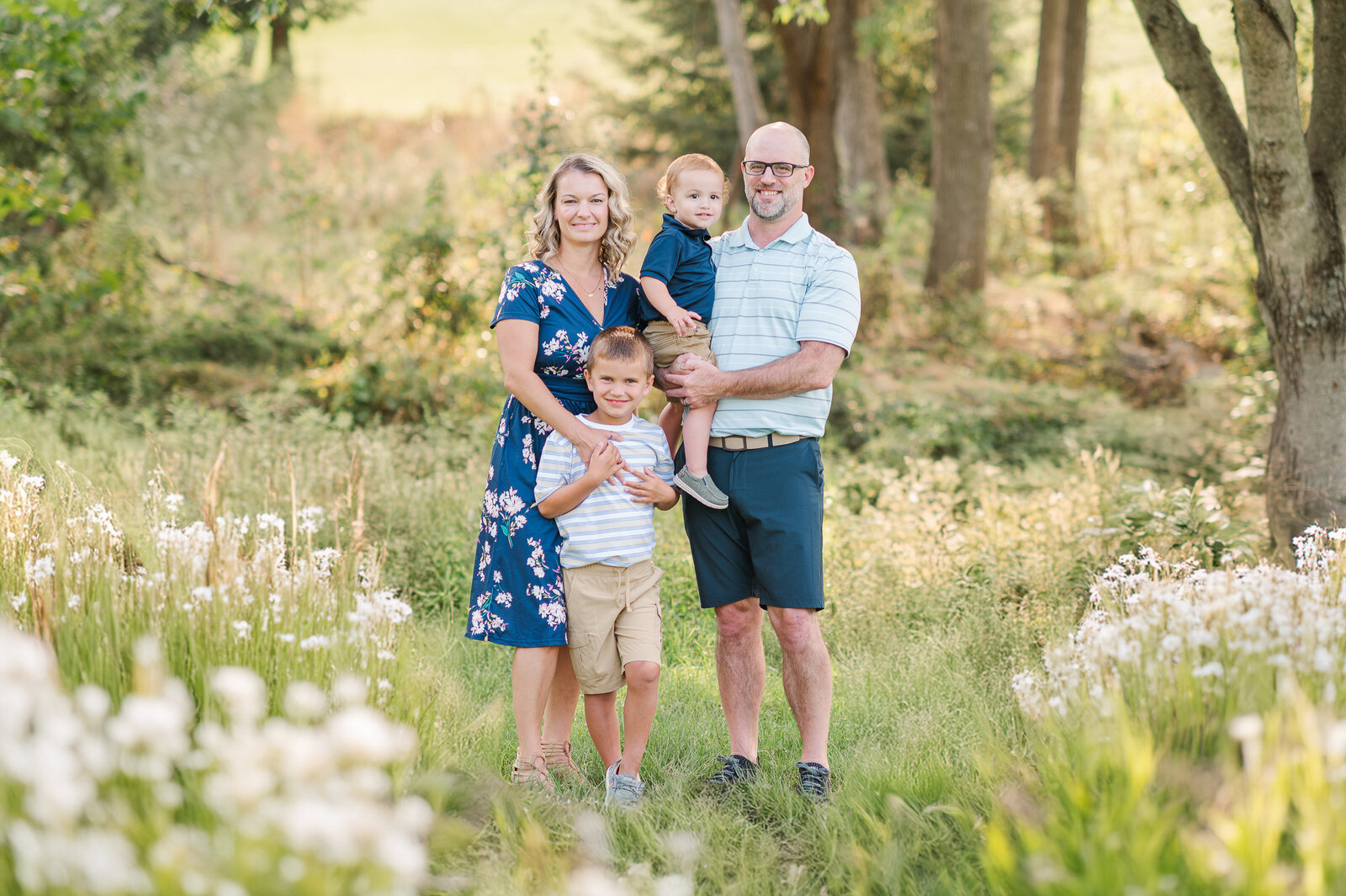 family of four standing in tall grasses and wild flowers together in dover by york pa photographer
