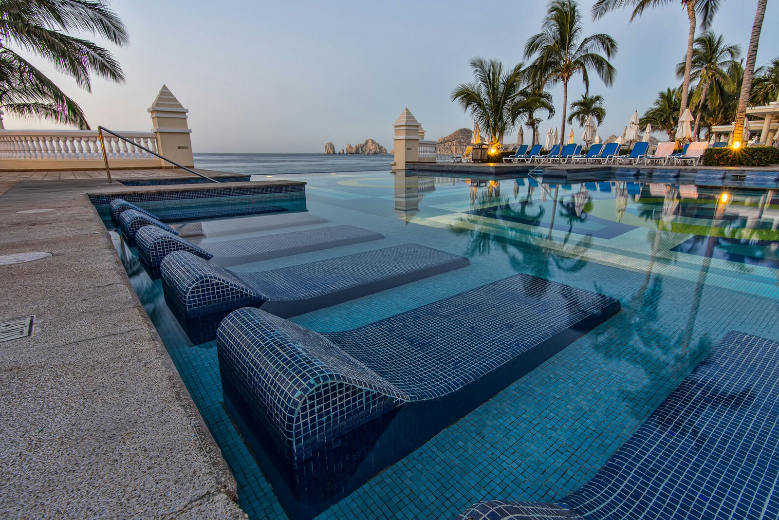 Large swimming pool surrounded by chairs and palm trees