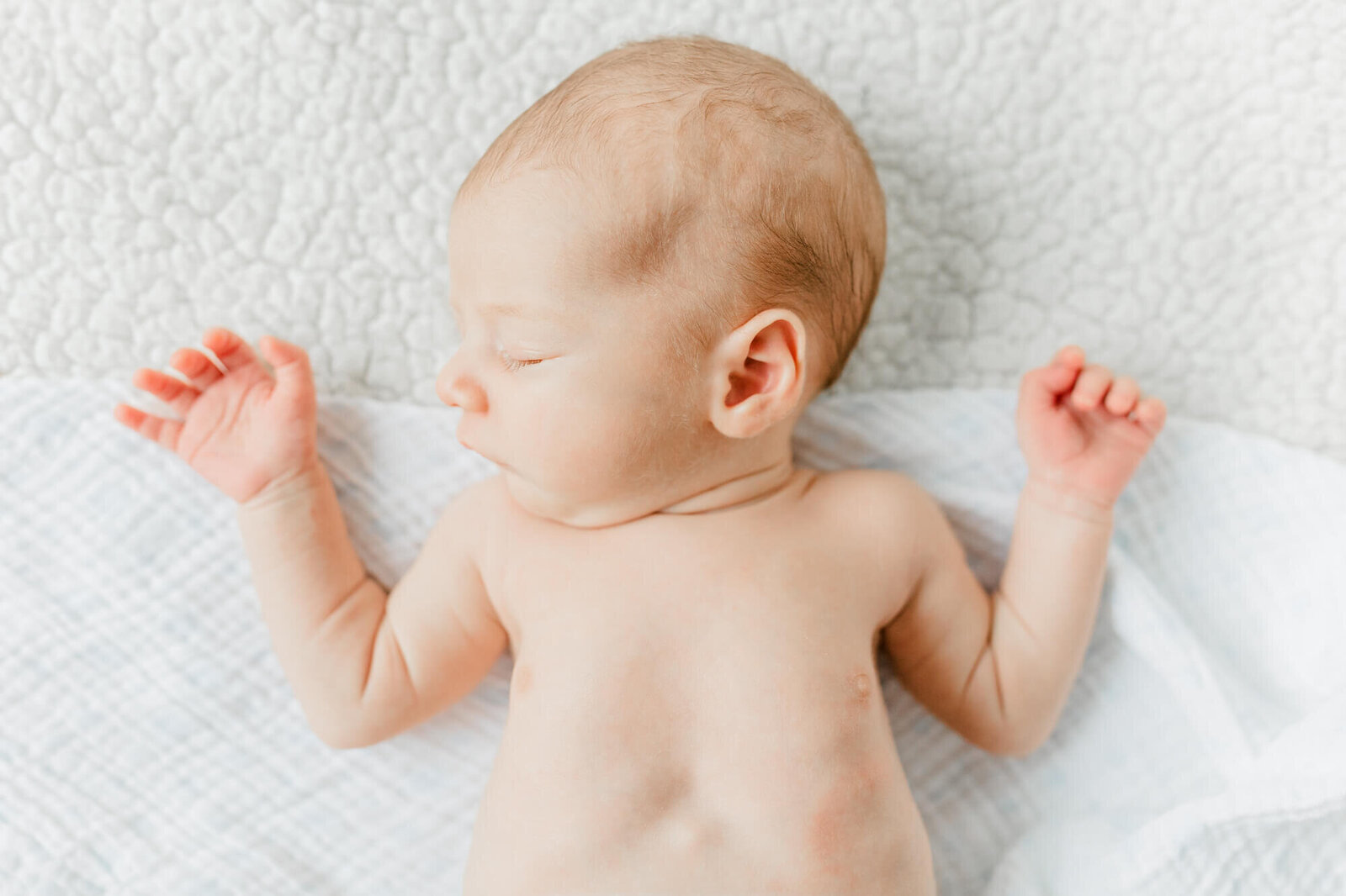 Sleeping baby laying with his arms out by his head