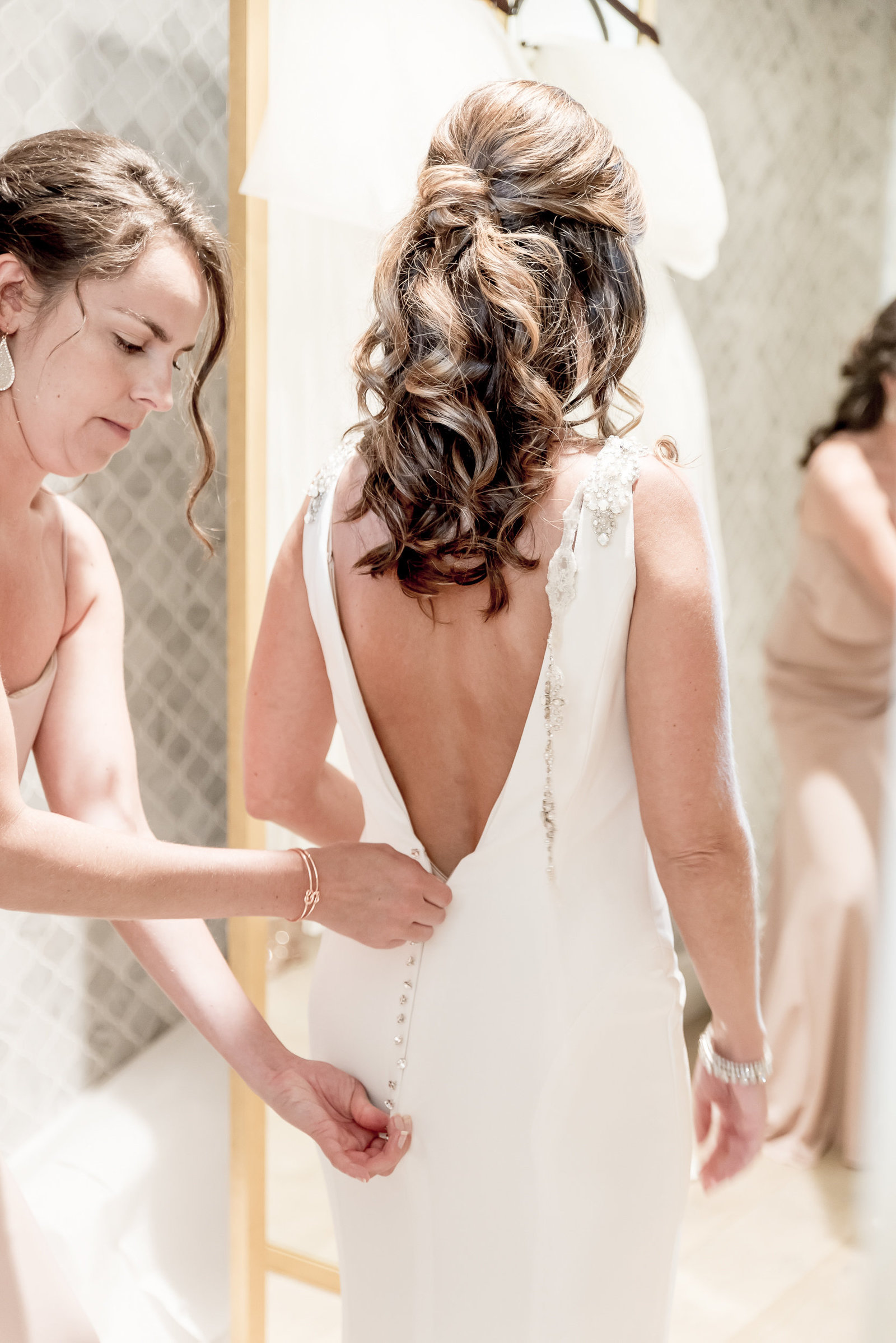 Bride getting her dress zipped by a bridesmaid
