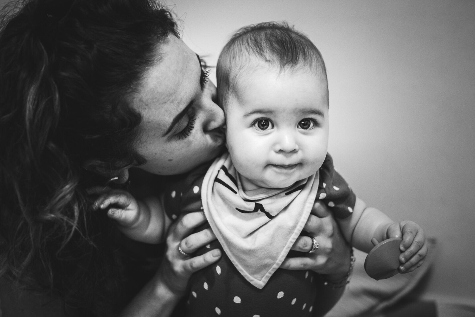 mother kisses her daughter in a black & white image