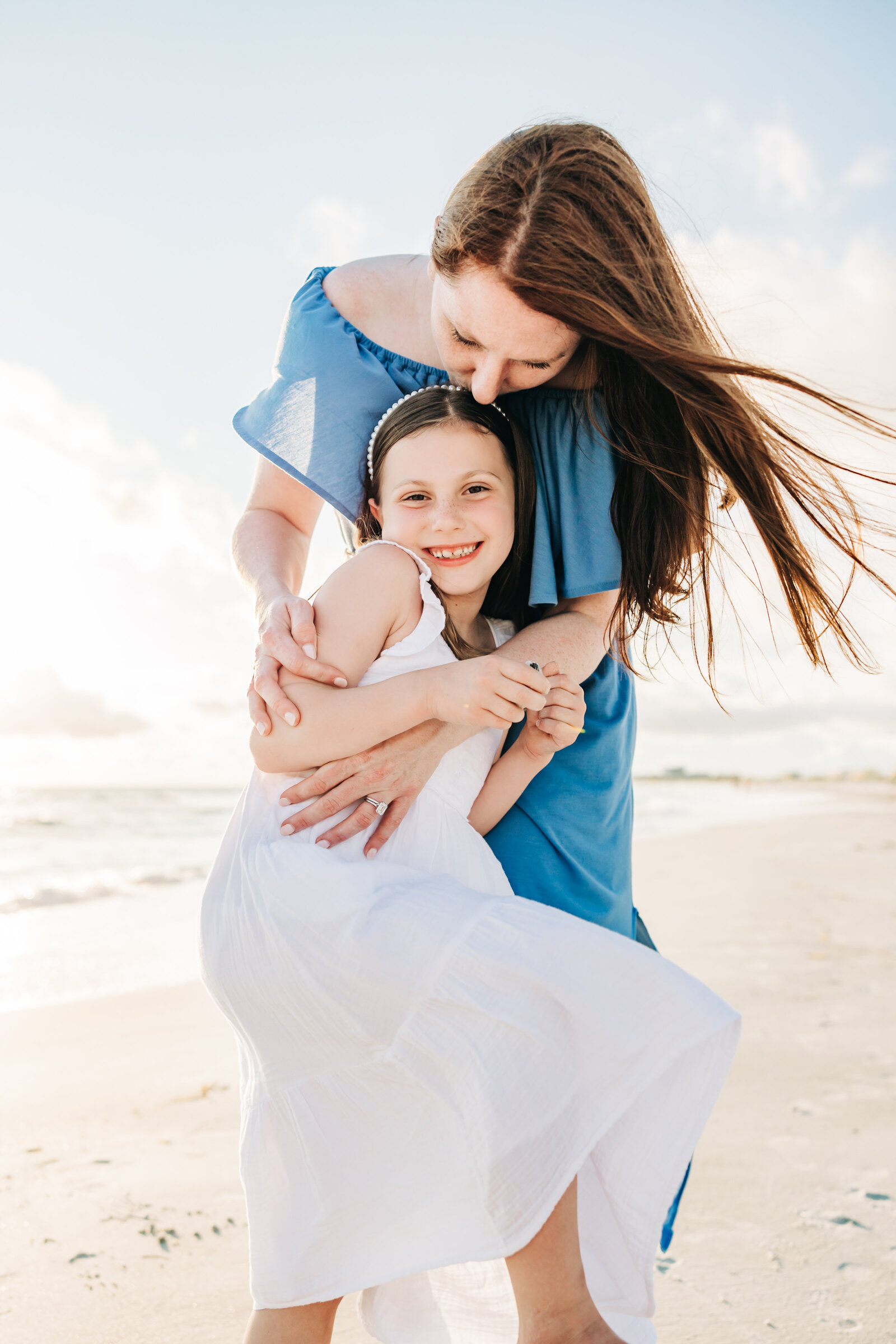 Photo of a mom in a blue dress and daughter in a white on a breezy beach day in st. pete
