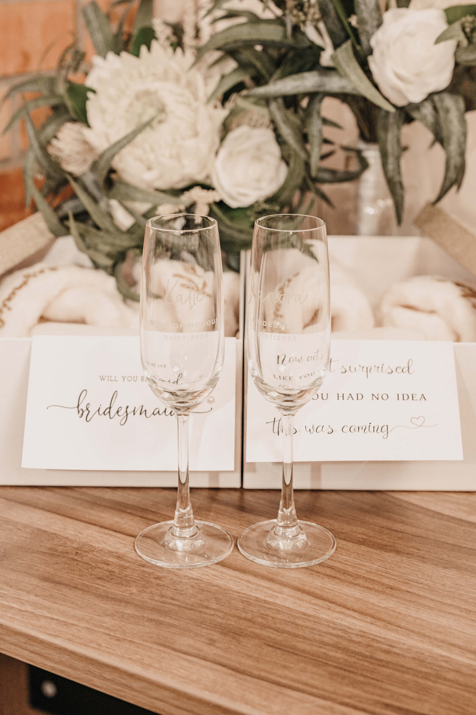 Two elegant wine glasses on a table beside a vibrant bouquet of flowers, creating a charming and inviting atmosphere.