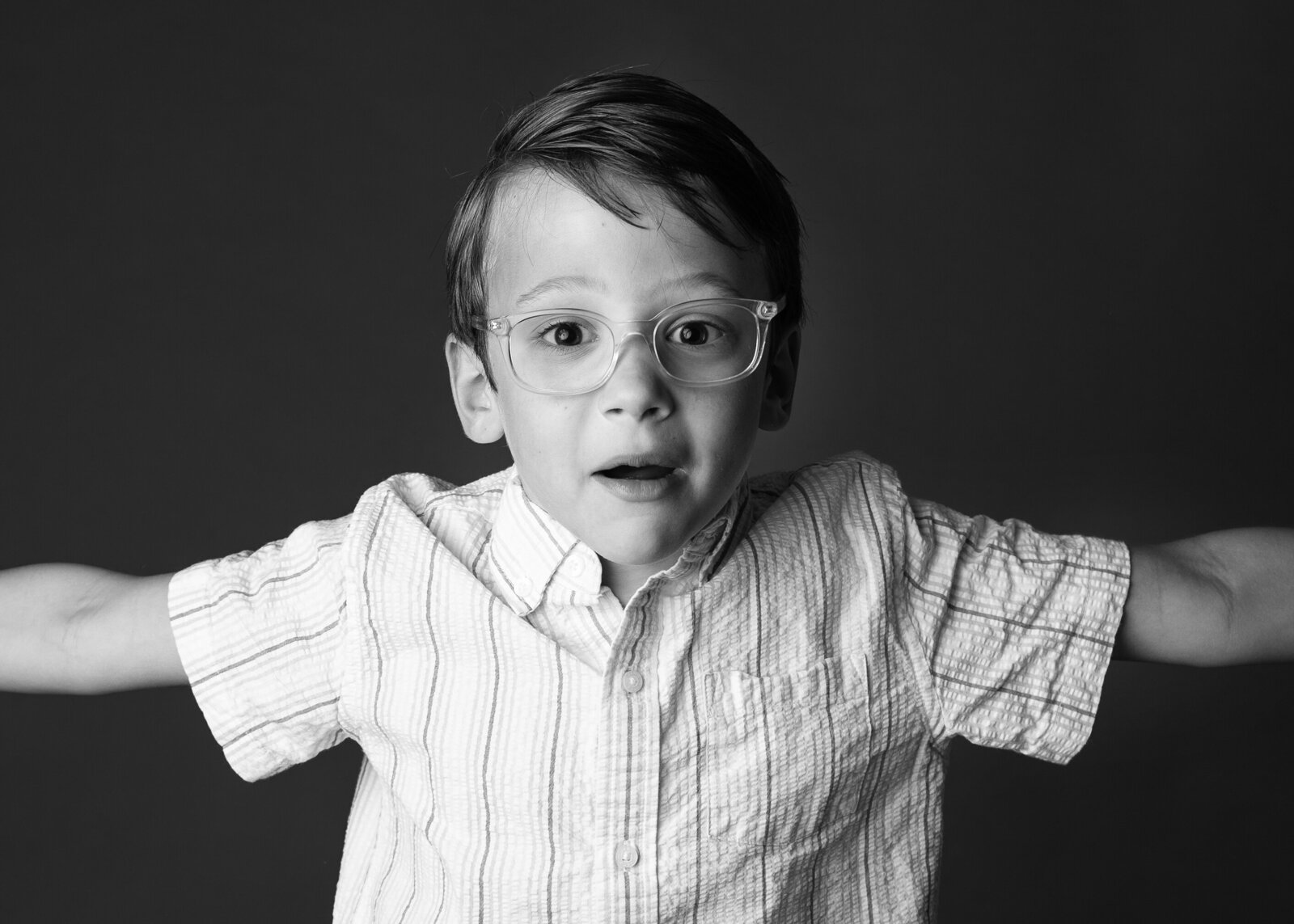 Black and white school portrait of young boy in glasses showing his personality.