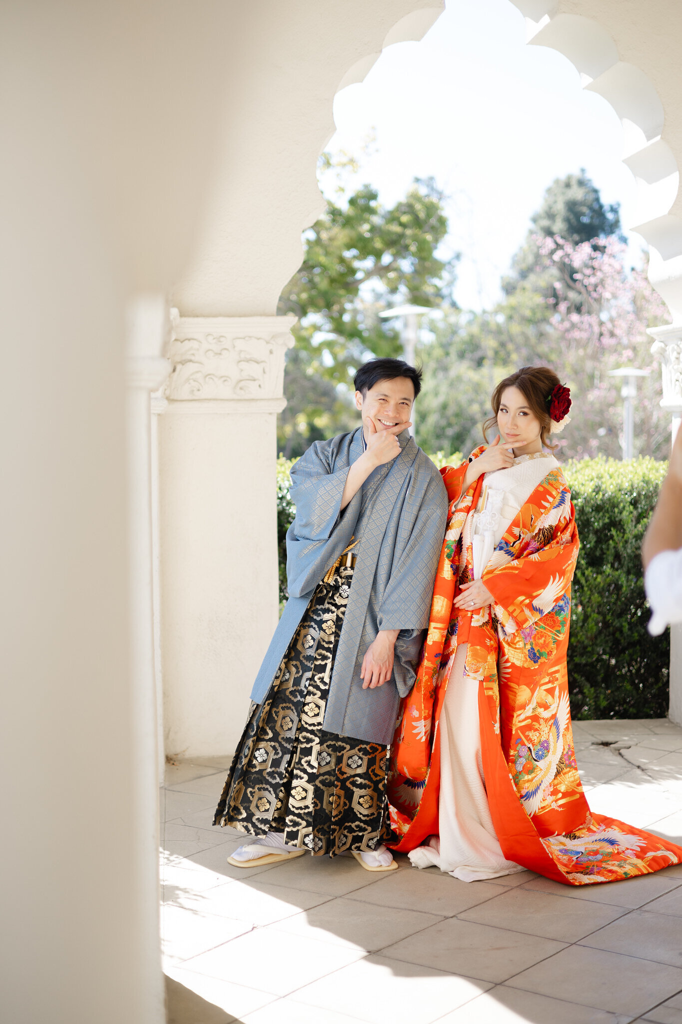 Bride and groom posing playfully in vibrant color uchikake and montsuki at Brand Park Glendale, Los Angeles California. Available for wedding kimono rental | 華やかな色打掛と紋付袴のカップルがブランドパーク・グレンデールで楽しくポーズ。ロサンゼルス カリフォルニアの着物レンタル。