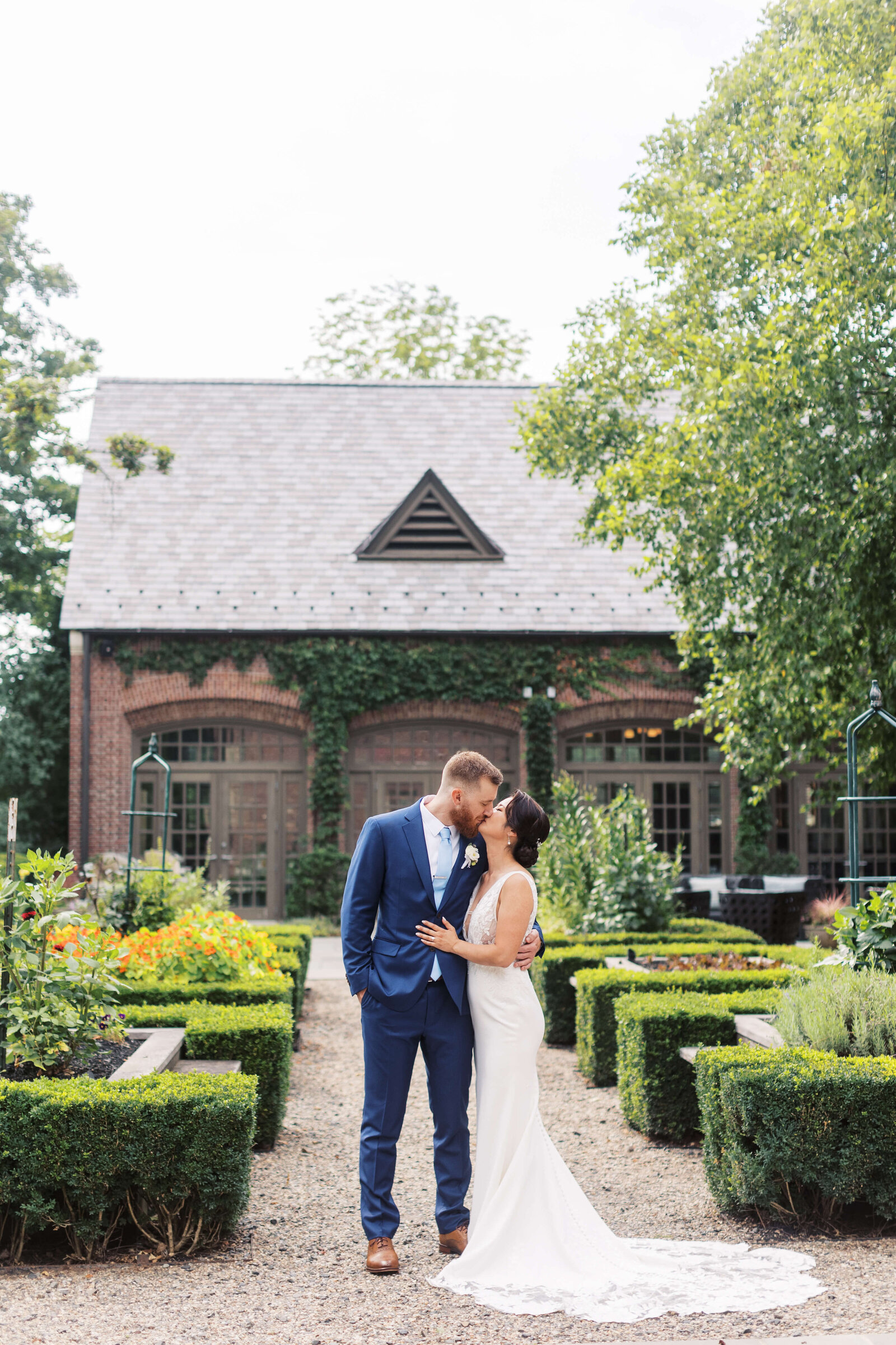 Bride and groom share a kiss in the courtyard in front of Ninety Acres at Natirar.