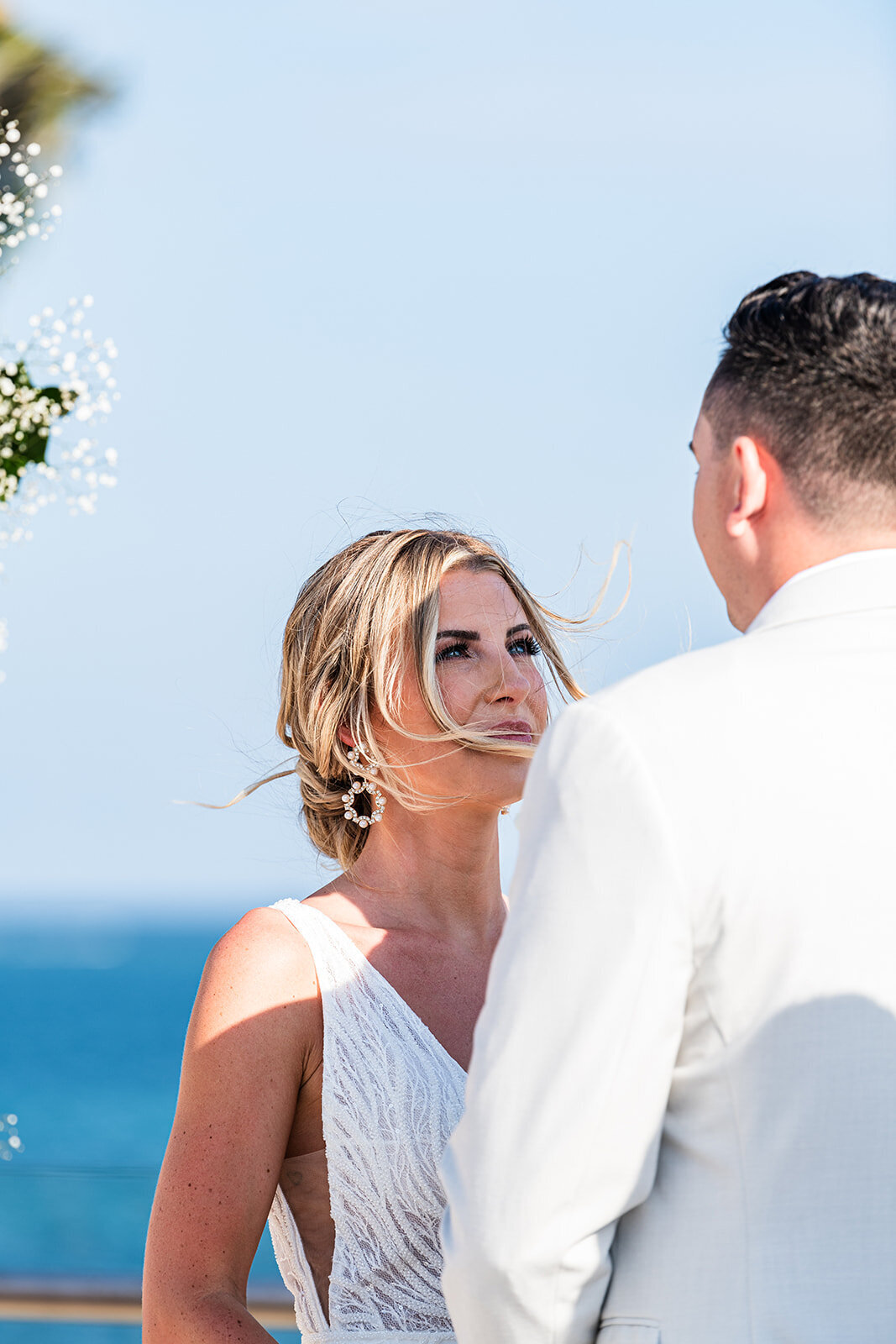 A touching moment as the bride and groom exchange vows with the ocean as a backdrop, captured during a destination wedding by CMH Studios