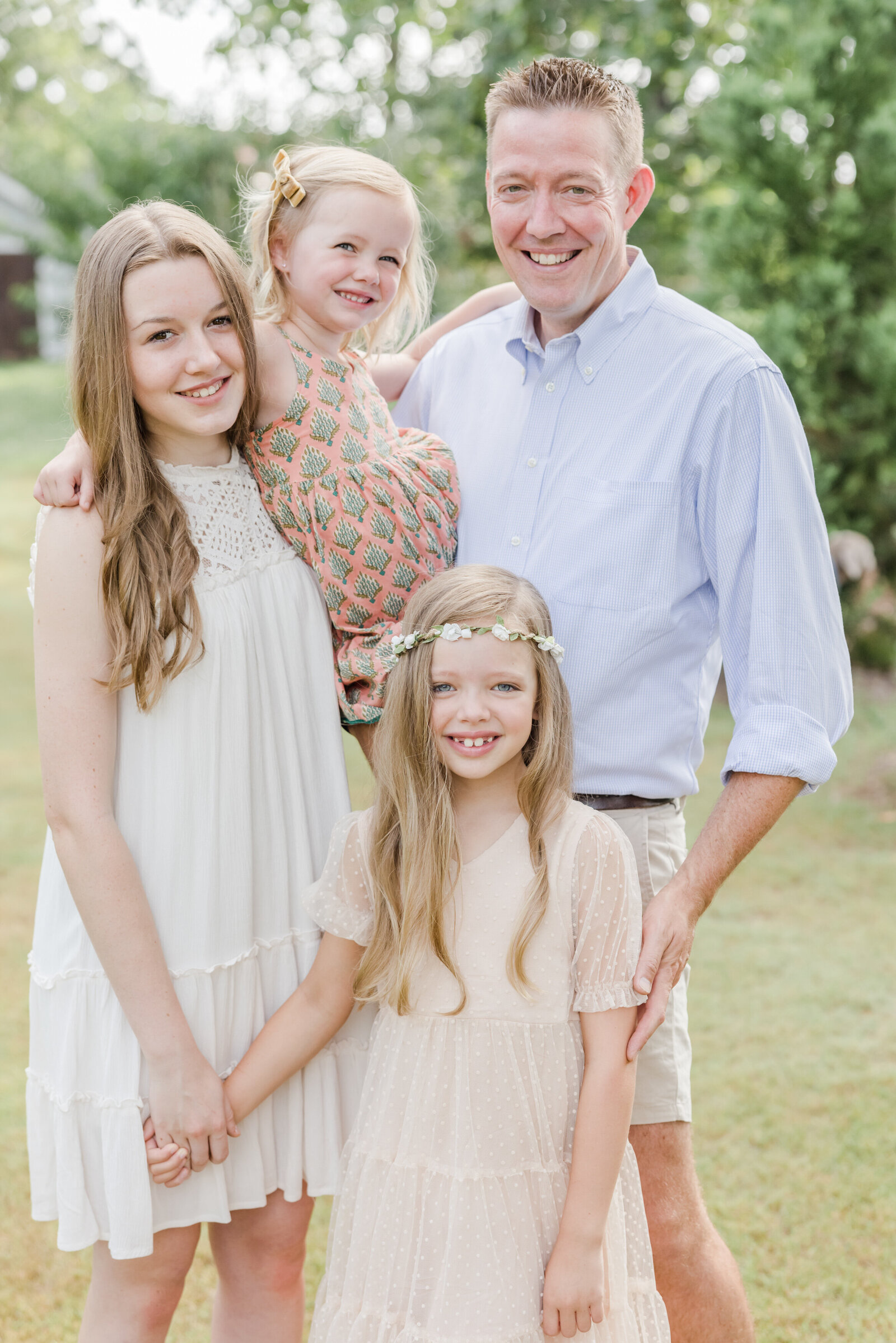 Father smiling and standing with his three daughters.