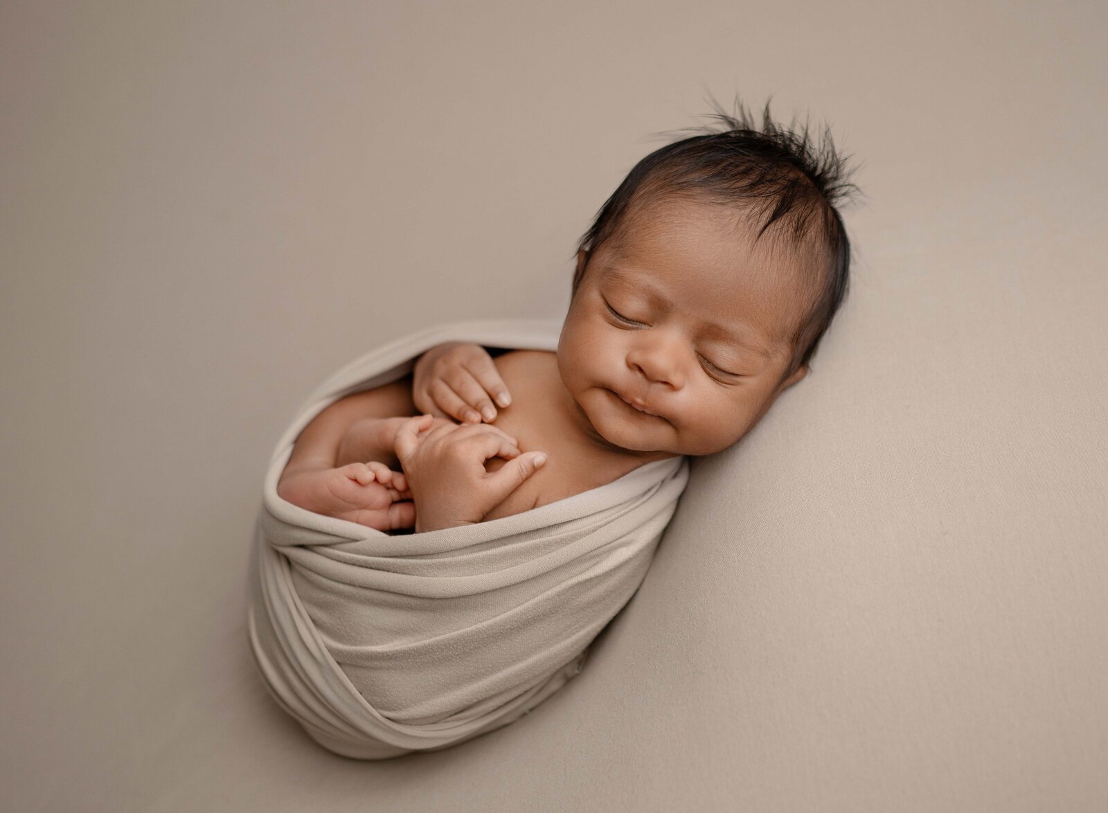 Marietta Family Photographer taken newborn baby photo swaddled in tan wrap.