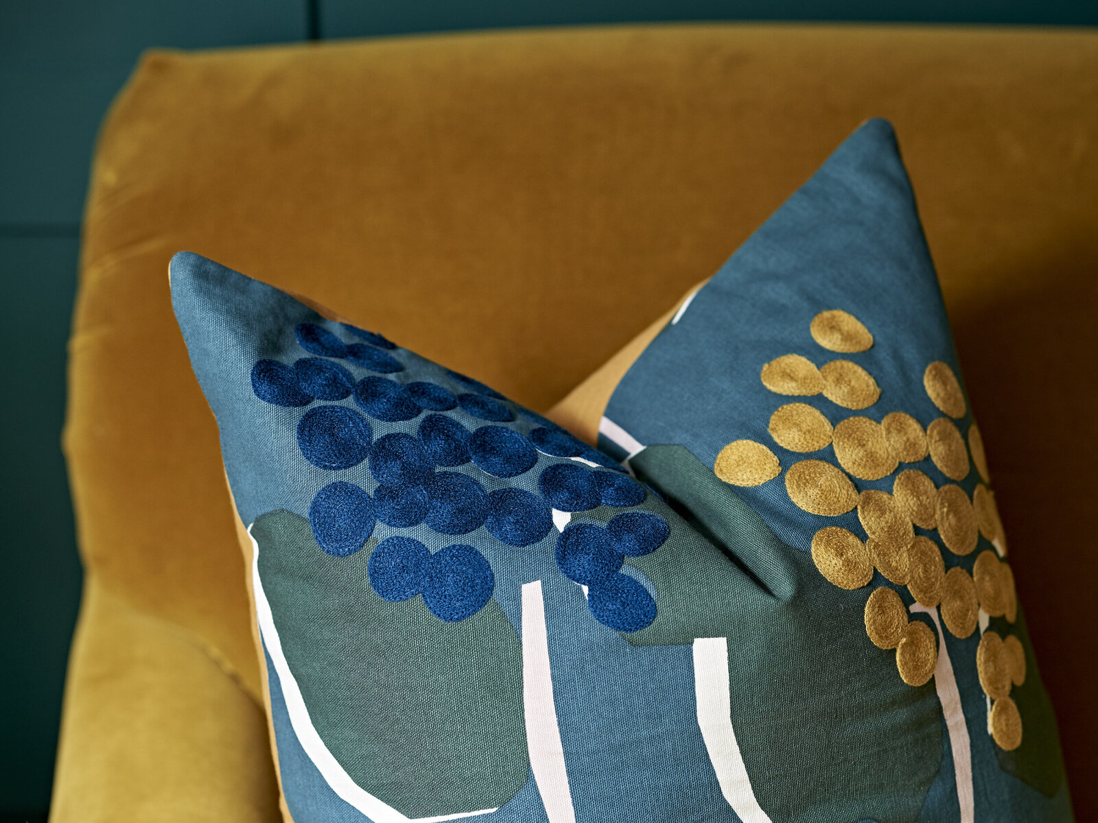 Detail of textured decorative pillow with teal and burnt yellow