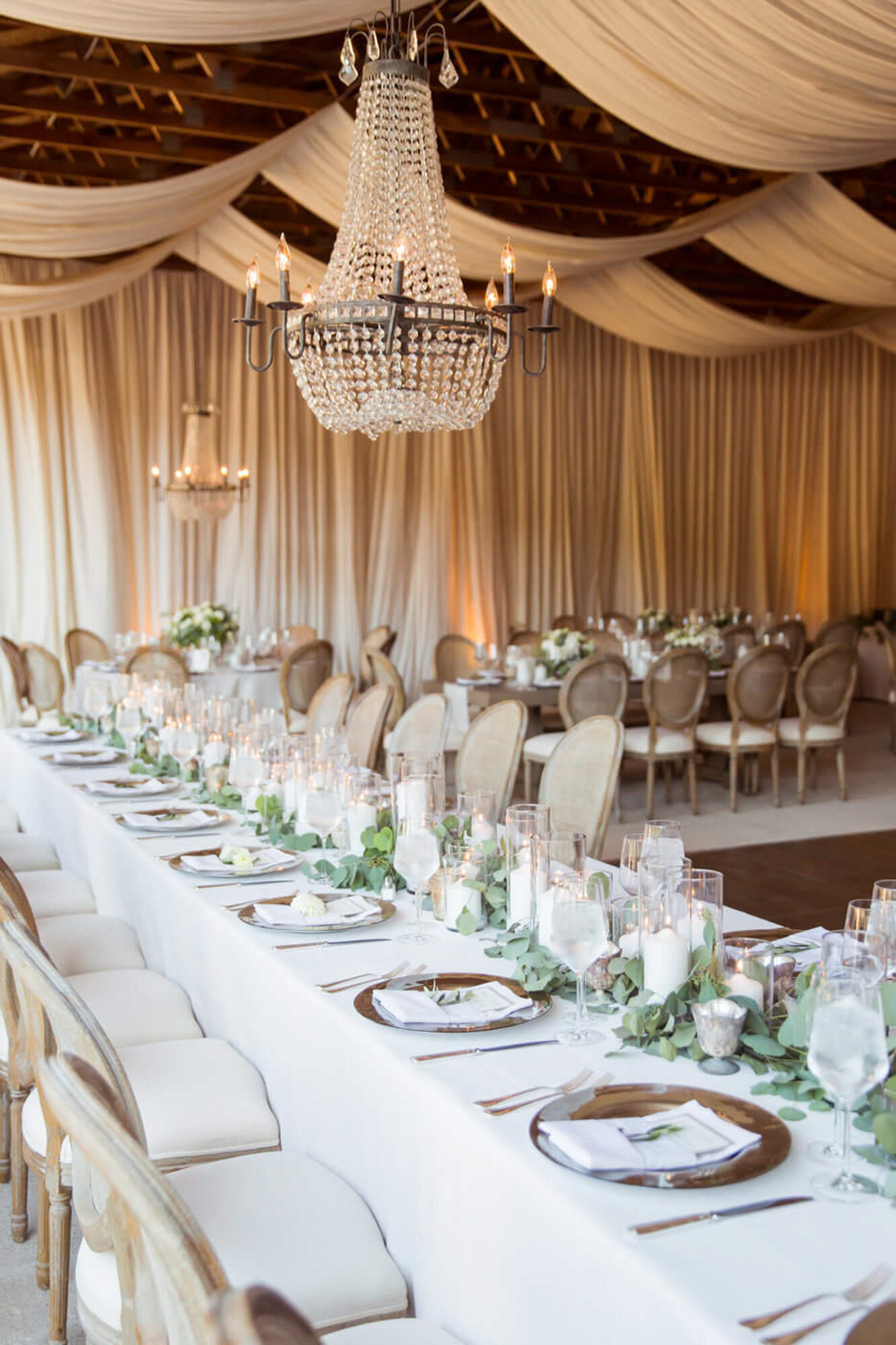 Elegant wedding set-up, tables  and chairs with floral centerpieces and a grand chandelier