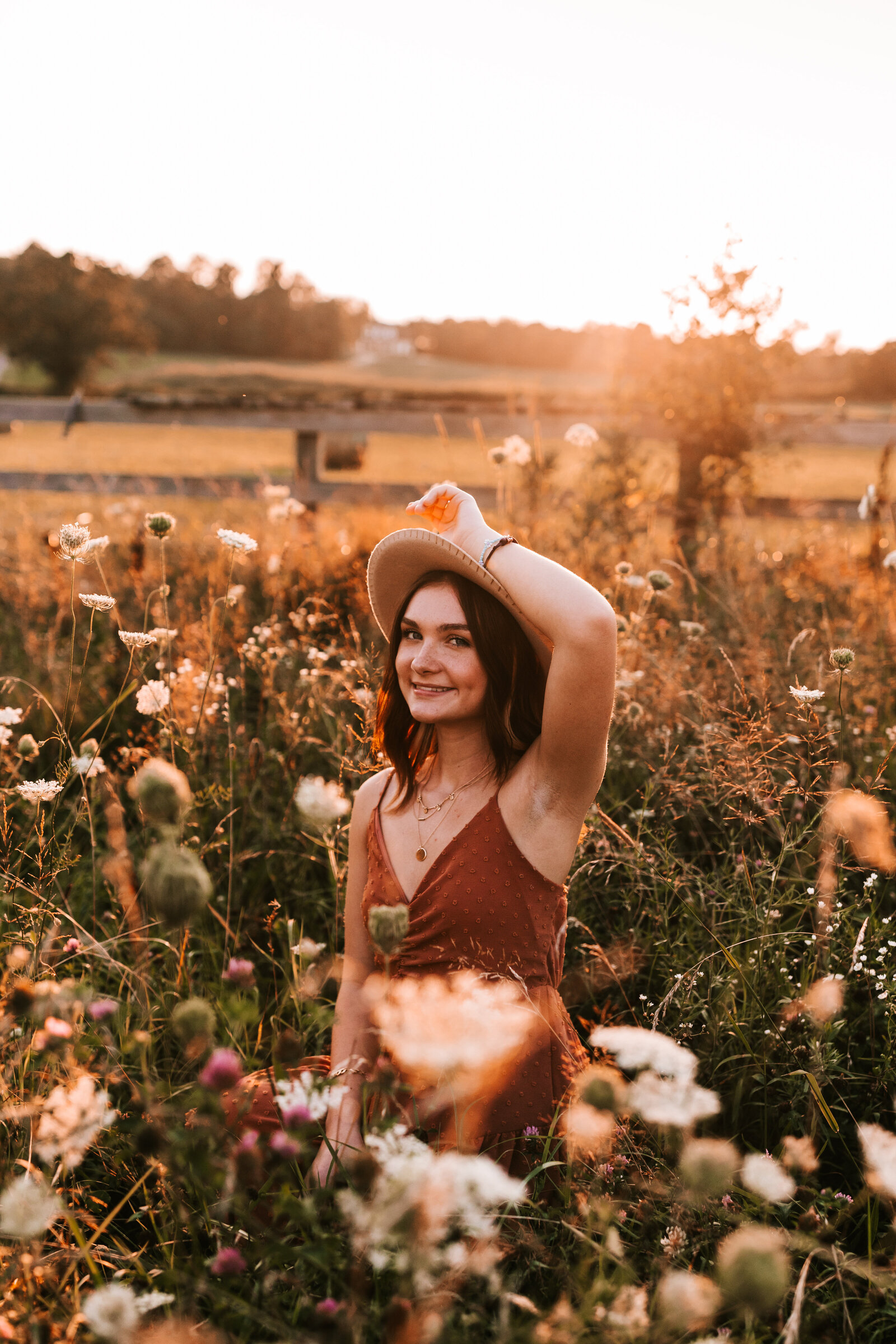 senior sitting in a field of flowers during a sunset senior 2022 girl