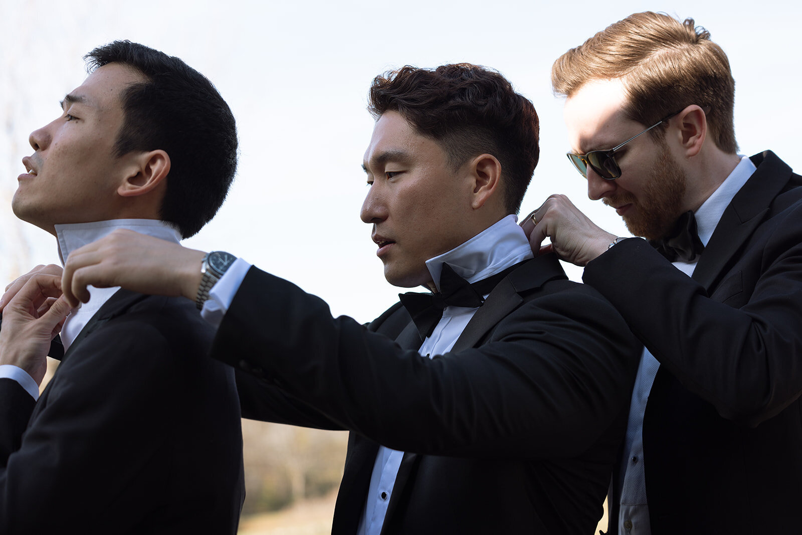 Groomsmen line up in black suits while fixing each others ties before a ceremony in Franklin, TN.
