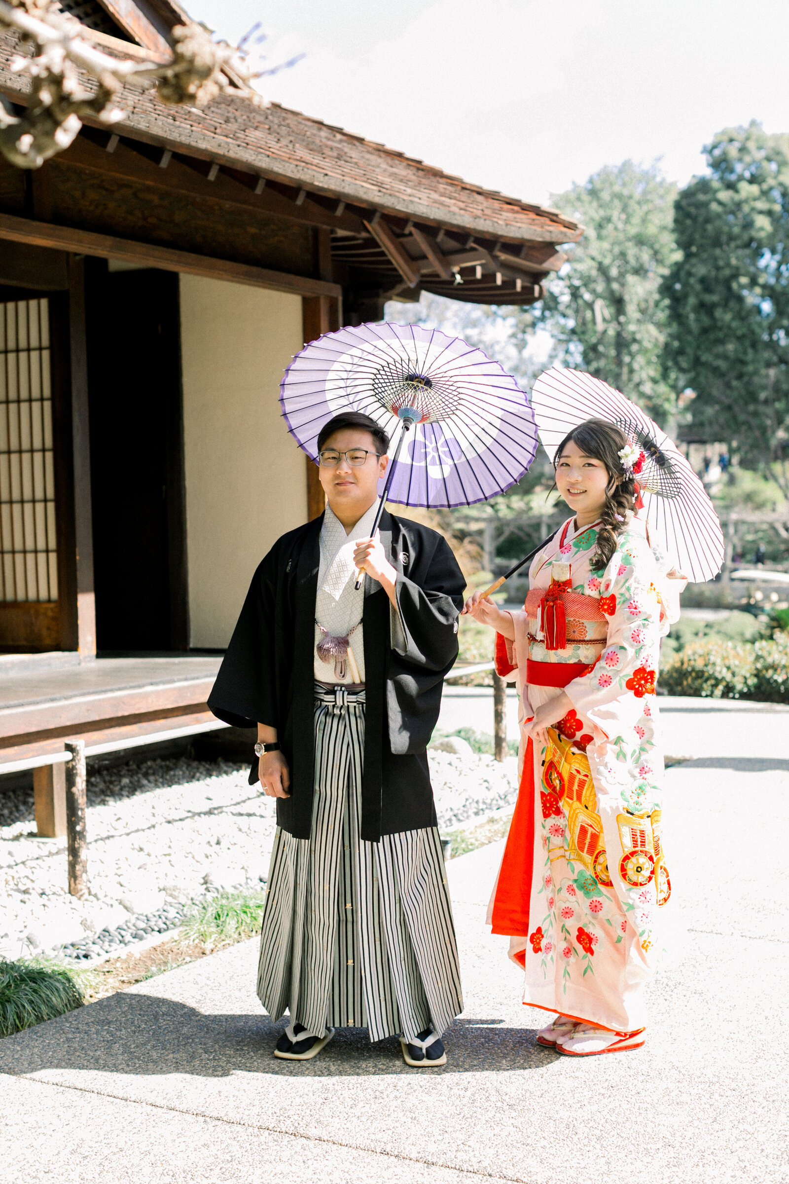 Bride in colorful wedding kimono rental and groom in montsuki haori hakama standing at a traditional wooden gate, The Huntington Library Japanese Garden, Los Angeles California | 花嫁が華やかな打掛をレンタル、新郎が紋付羽織袴でハンティントンライブラリー日本庭園の門にて