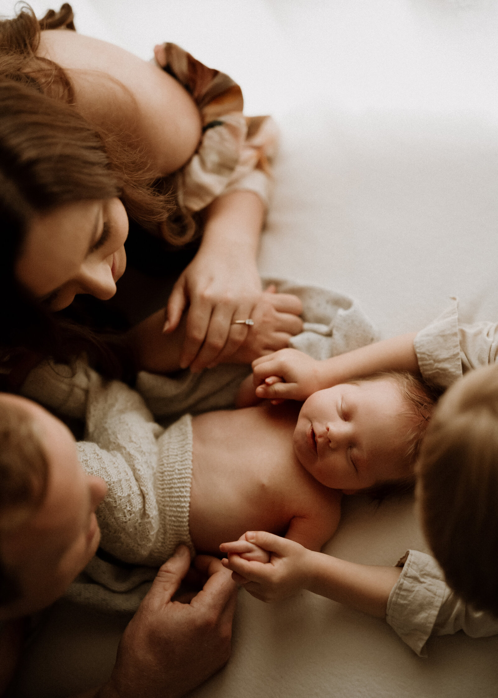 Newborn and parents studio photoshoot in Perth, featuring a timeless and loving embrace of a family with their newborn.