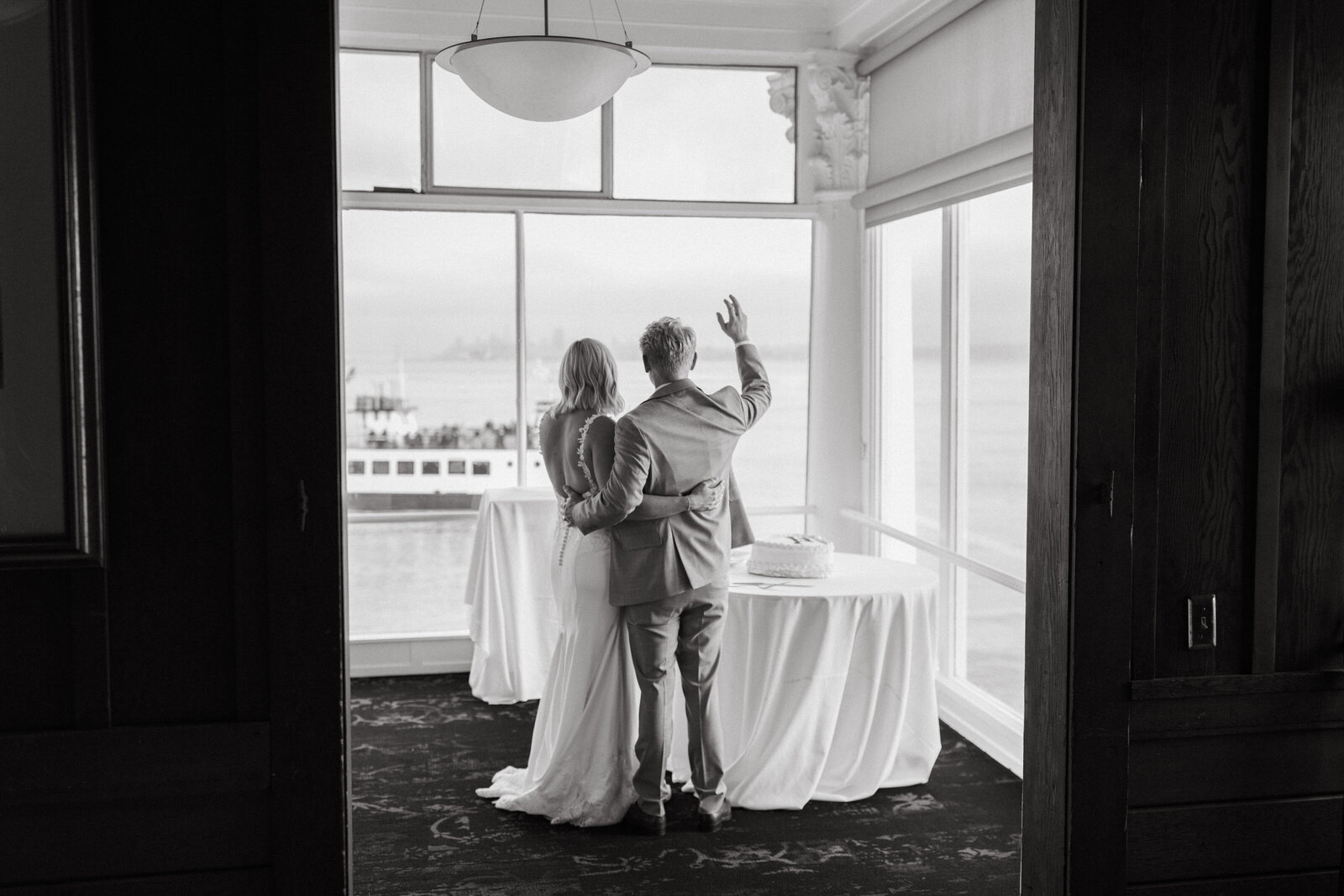 Bride and groom waving at a passing ferry boat on wedding day