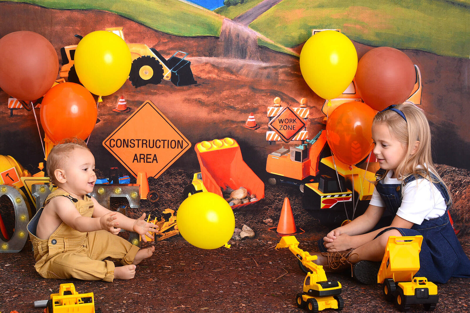siblings play together at a costruction themed first birthday photoshoot