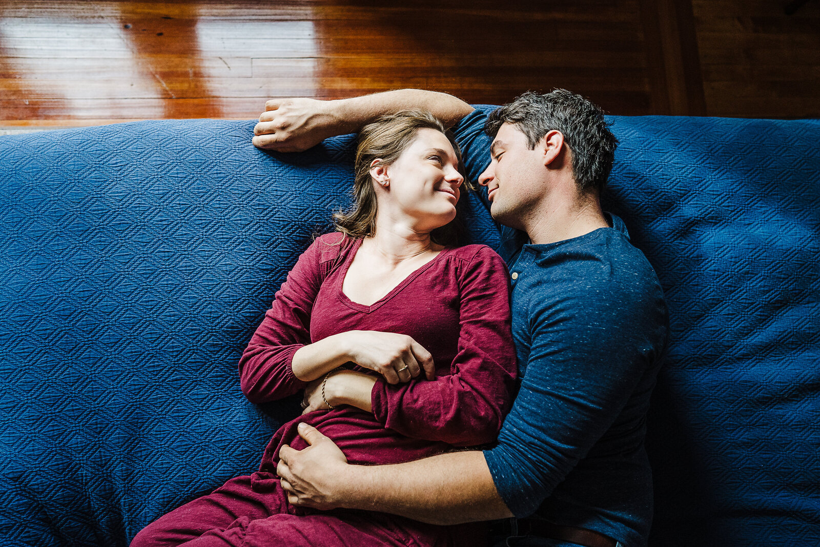 pregnant couple snuggles on bed during boston photoshoot