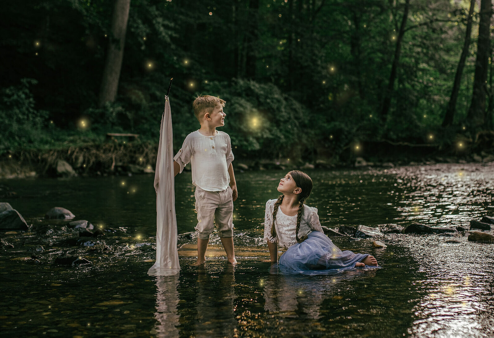 Boy and girl sitting on a raft in a creek at night with fireflies at Jerusalem Mill in Kingsville Maryland