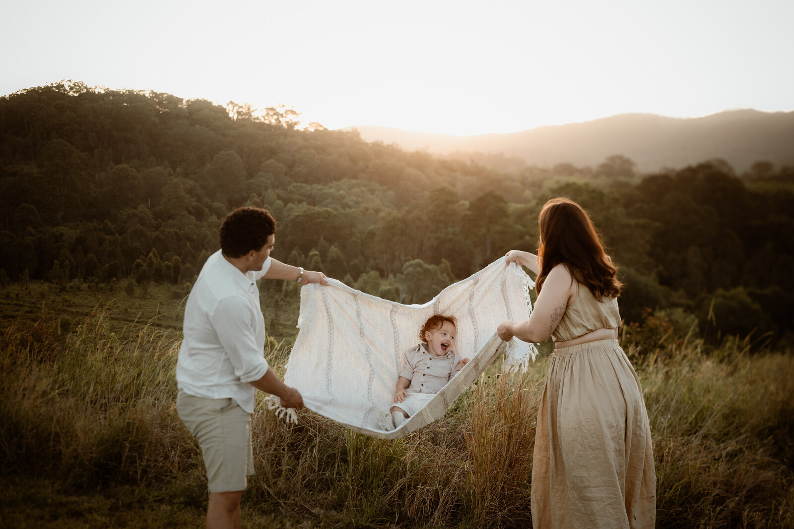 making family photos fun together, swinging on the picnic blanket with mum and dad