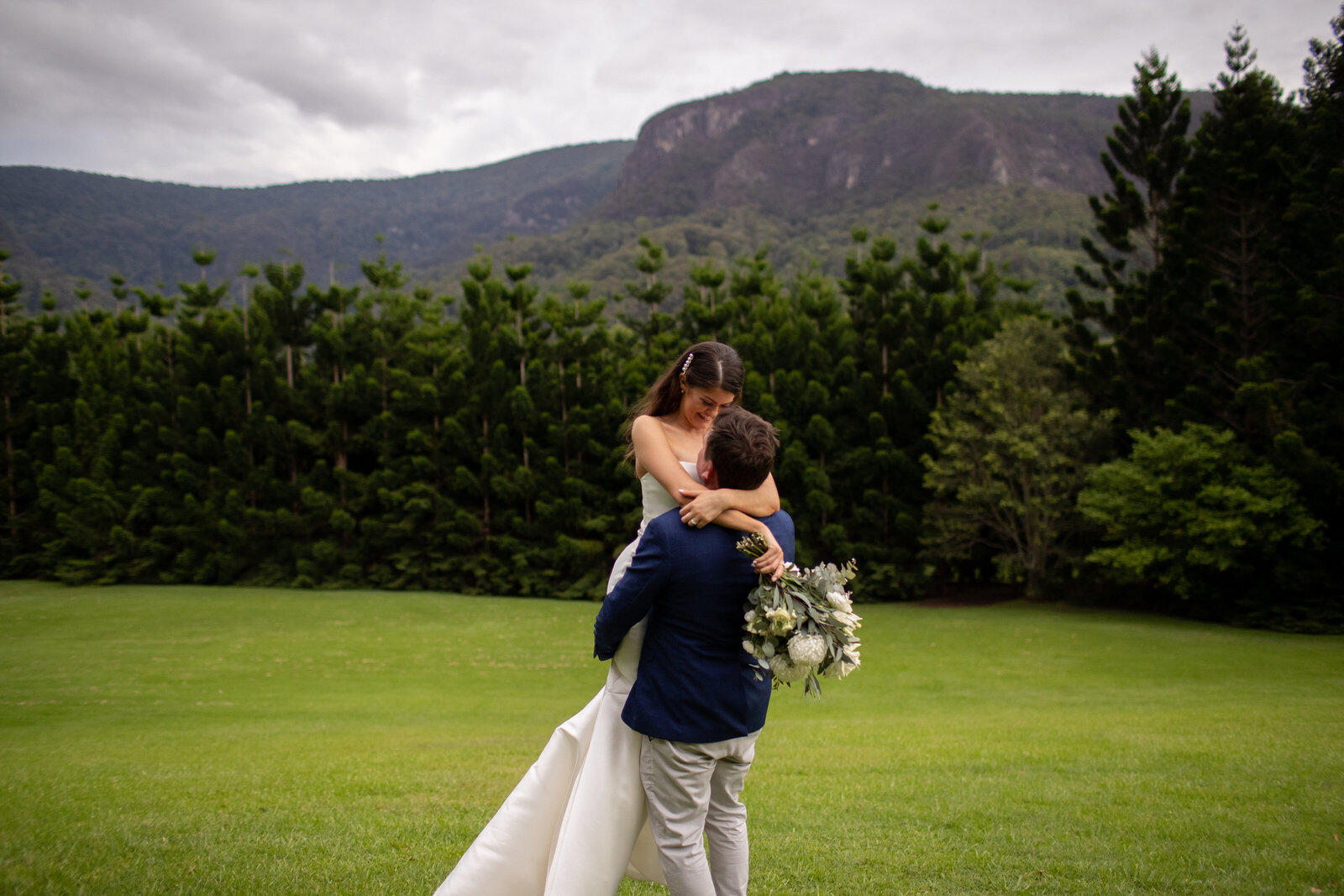 Groom lifts up bride and twirls in the mountain
