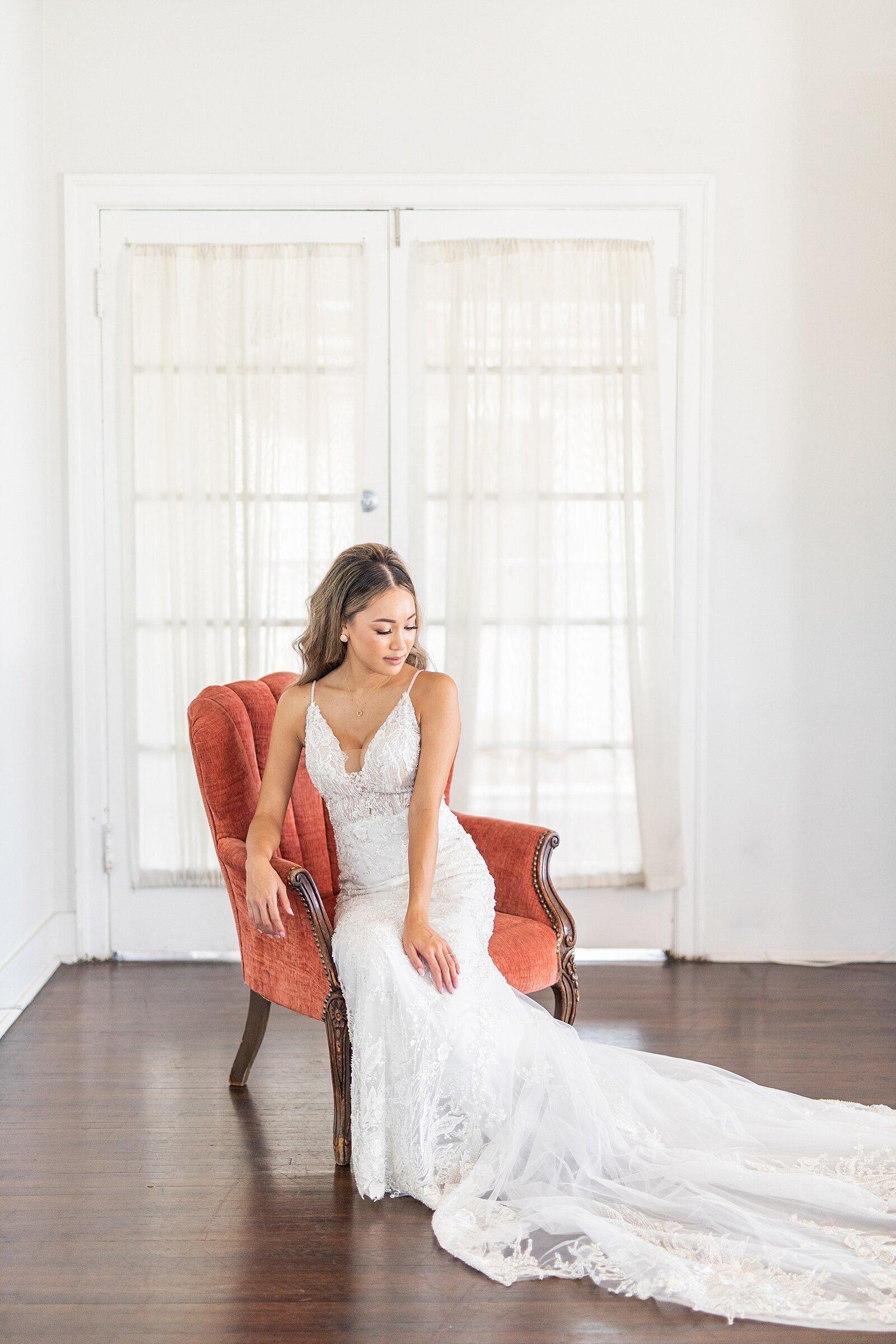 Bride sitting in velvet red chair at The Ebell of Long Beach.