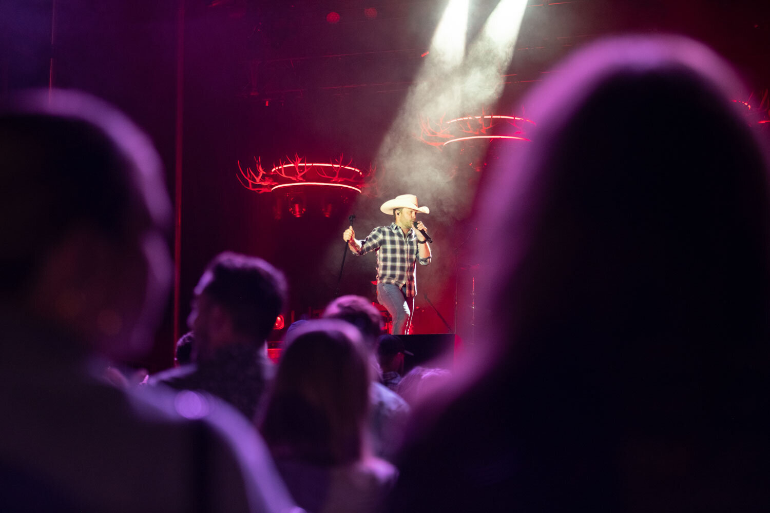 Singer in cowboy hat under spotlight performing on stage