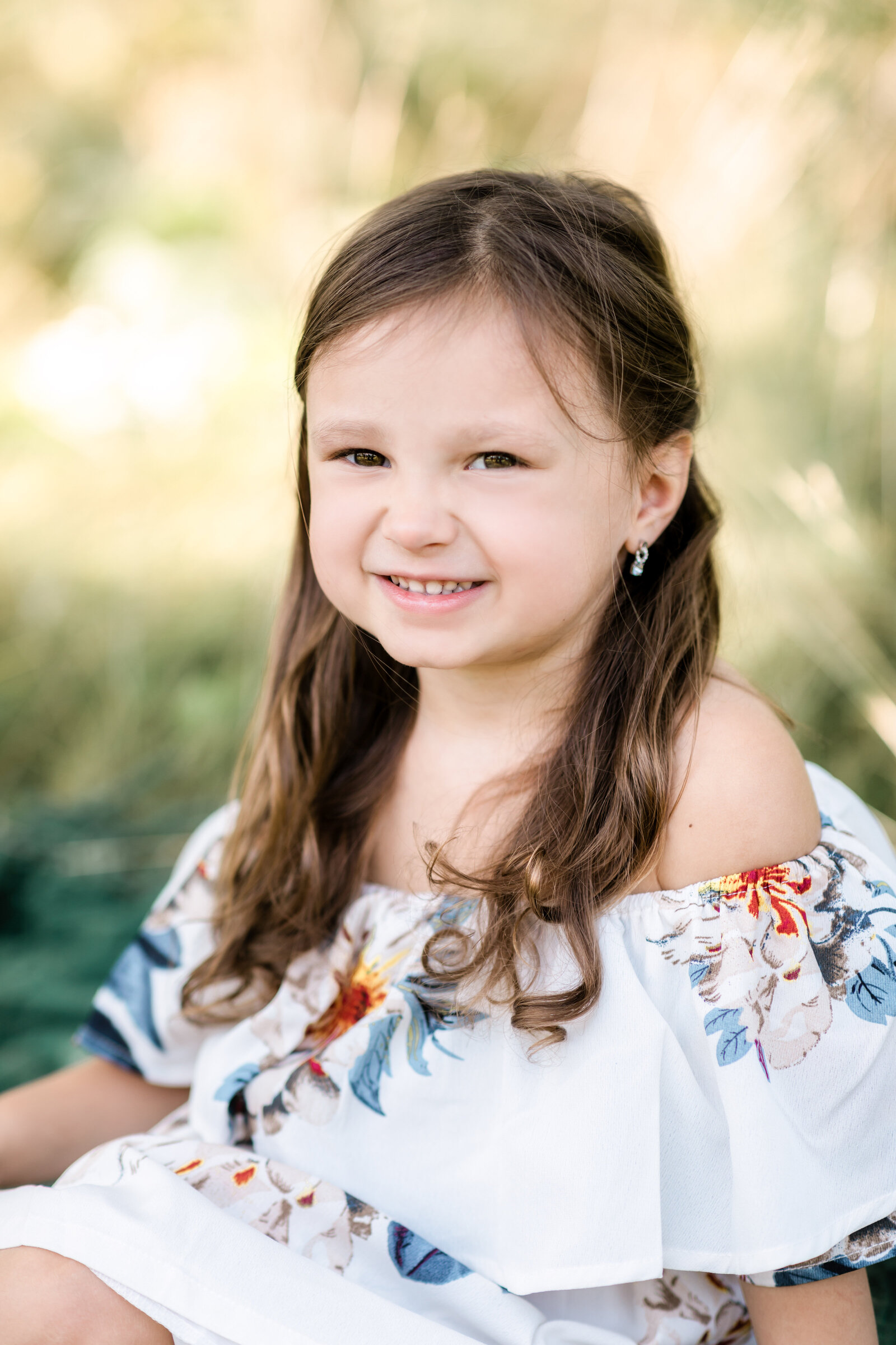 little girl in flowery dress posing for family photos