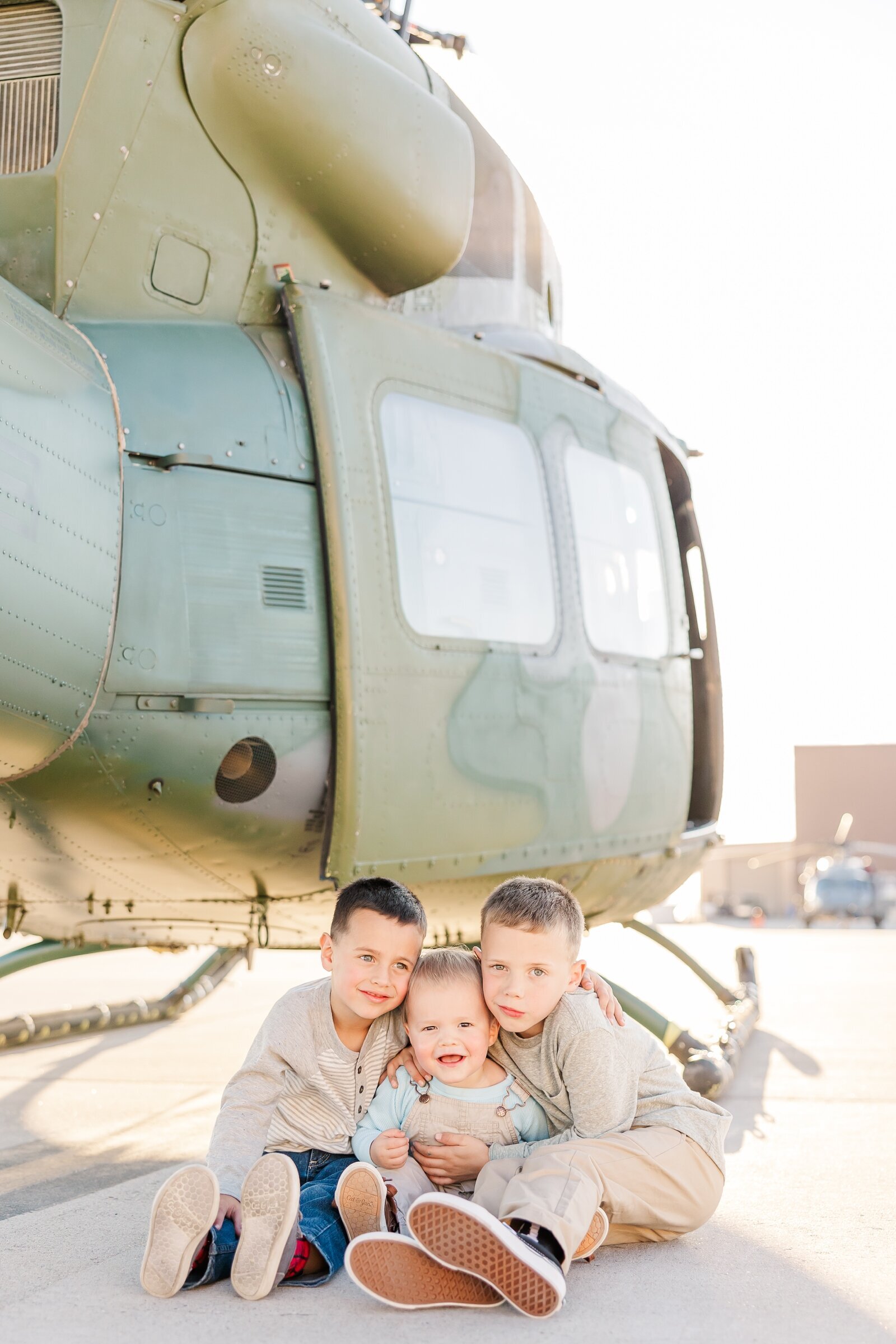 Brothers sitting on the ground in front of an Air Force helicopter