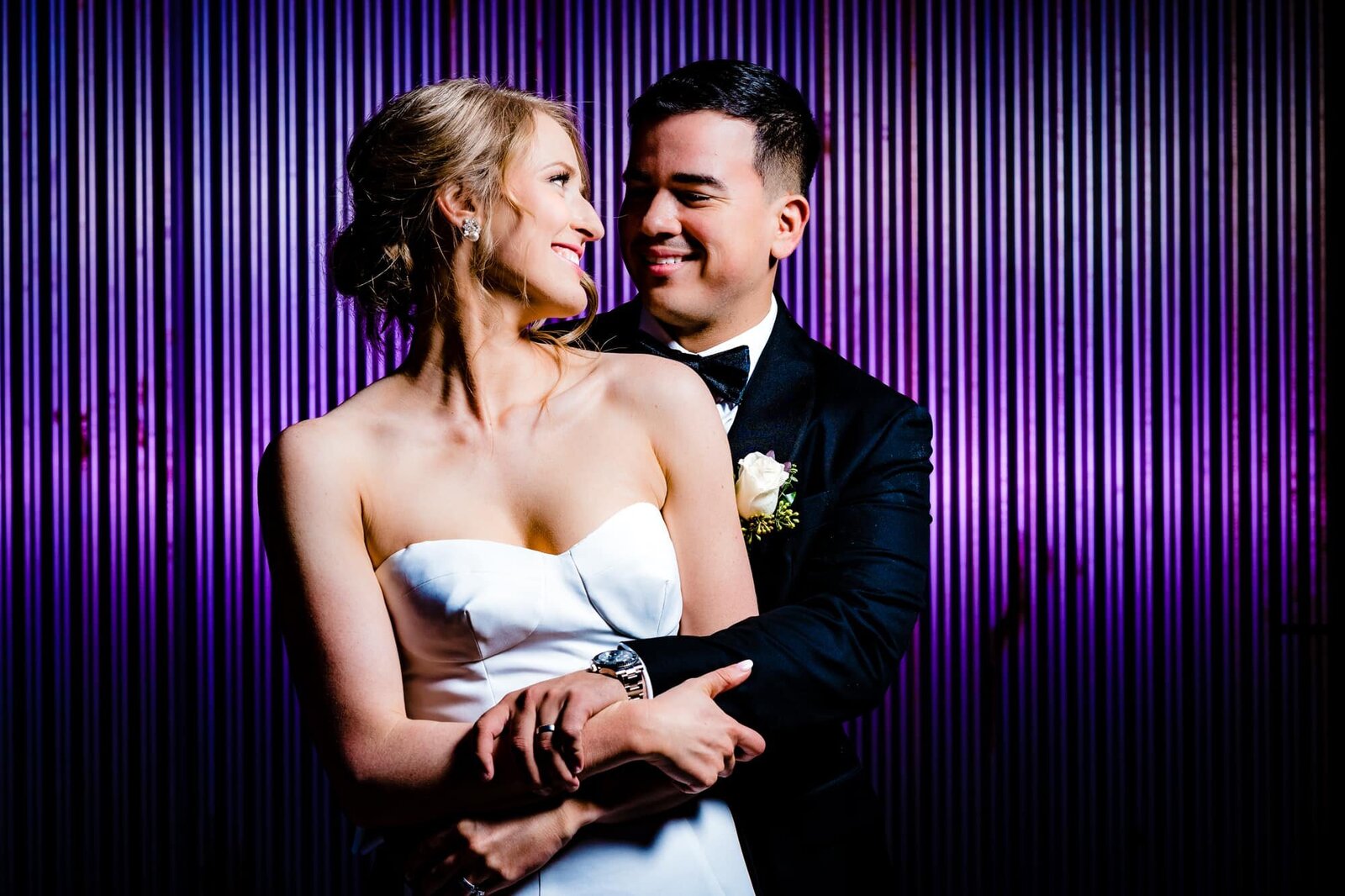 bride and groom embrace in front of a purple wall at their Durham, NC wedding