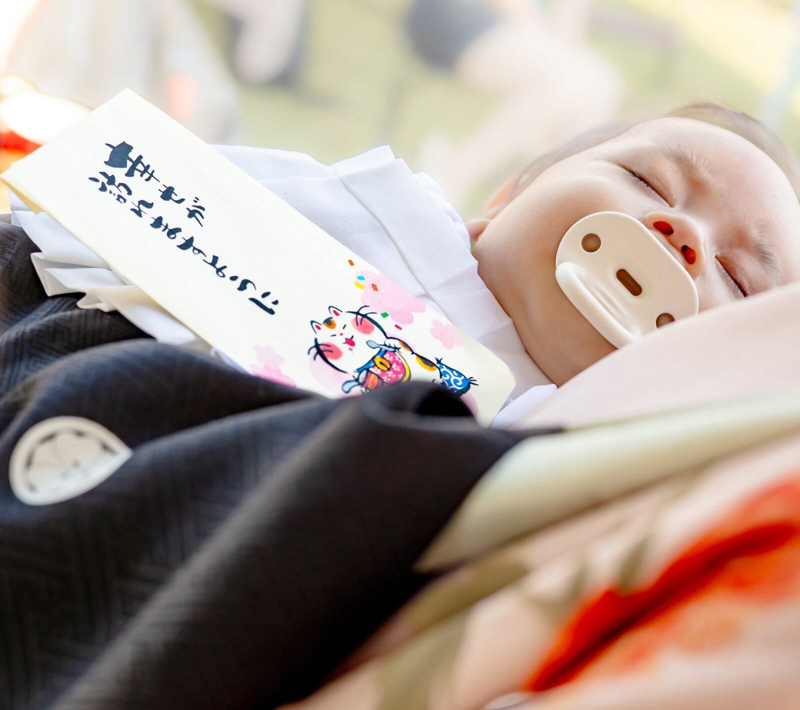 Sleeping baby with pacifier during Hatsumairi ceremony, wearing traditional white kimono bib | 初参り 赤ちゃん 寝顔 ロサンゼルス
