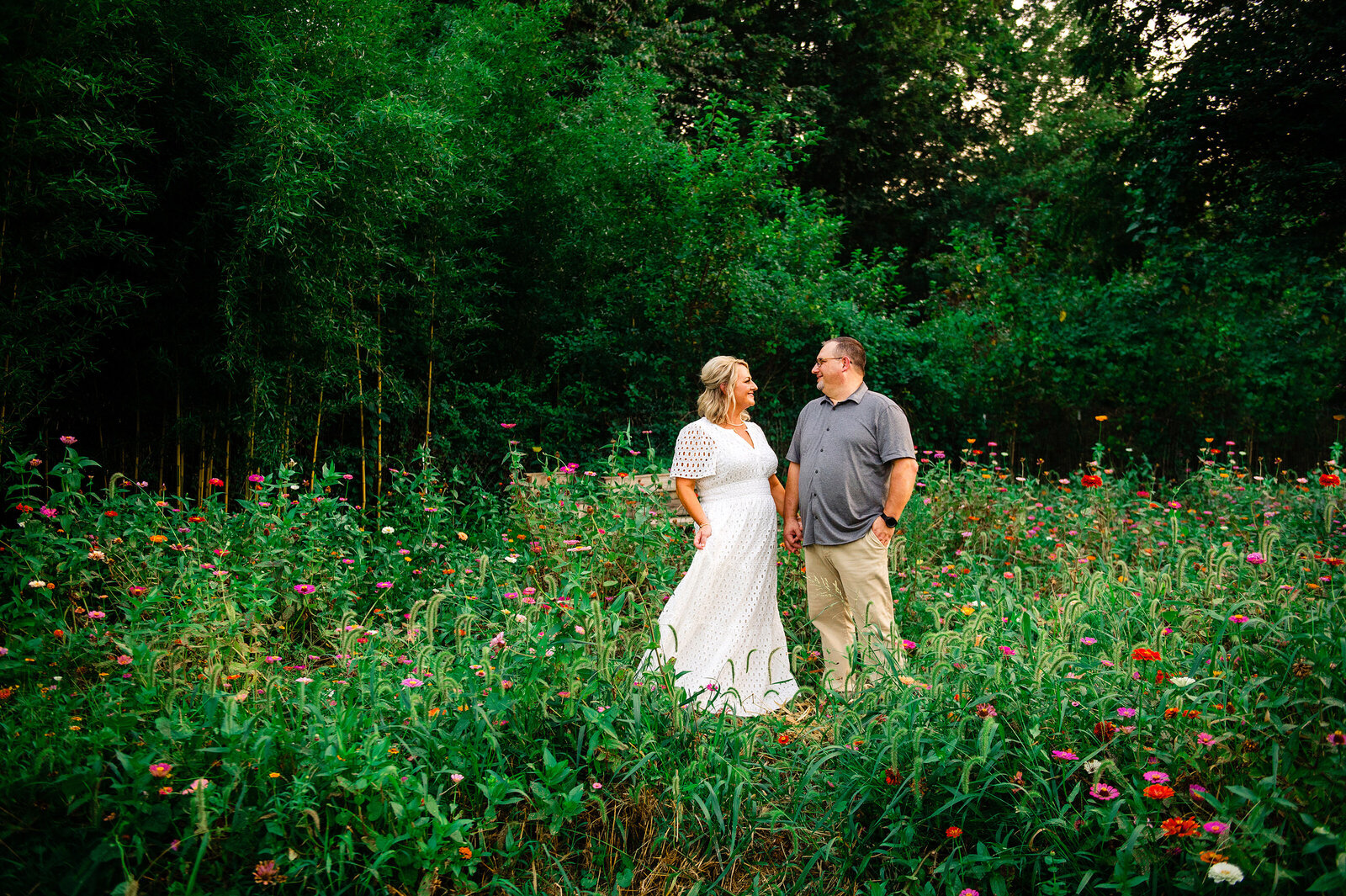 Girl wearing white dress holding hands with fiance in a flower field