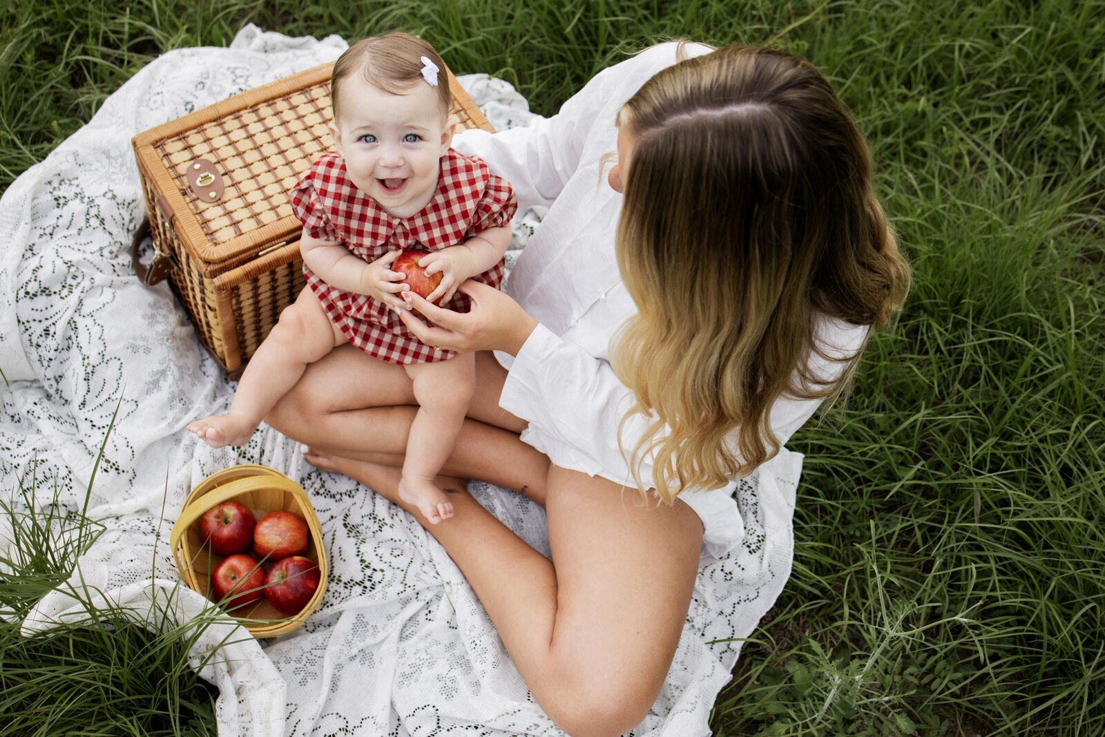 baby sits on mama's lap while at a mini session in Erwin Park in Mckinney Texas