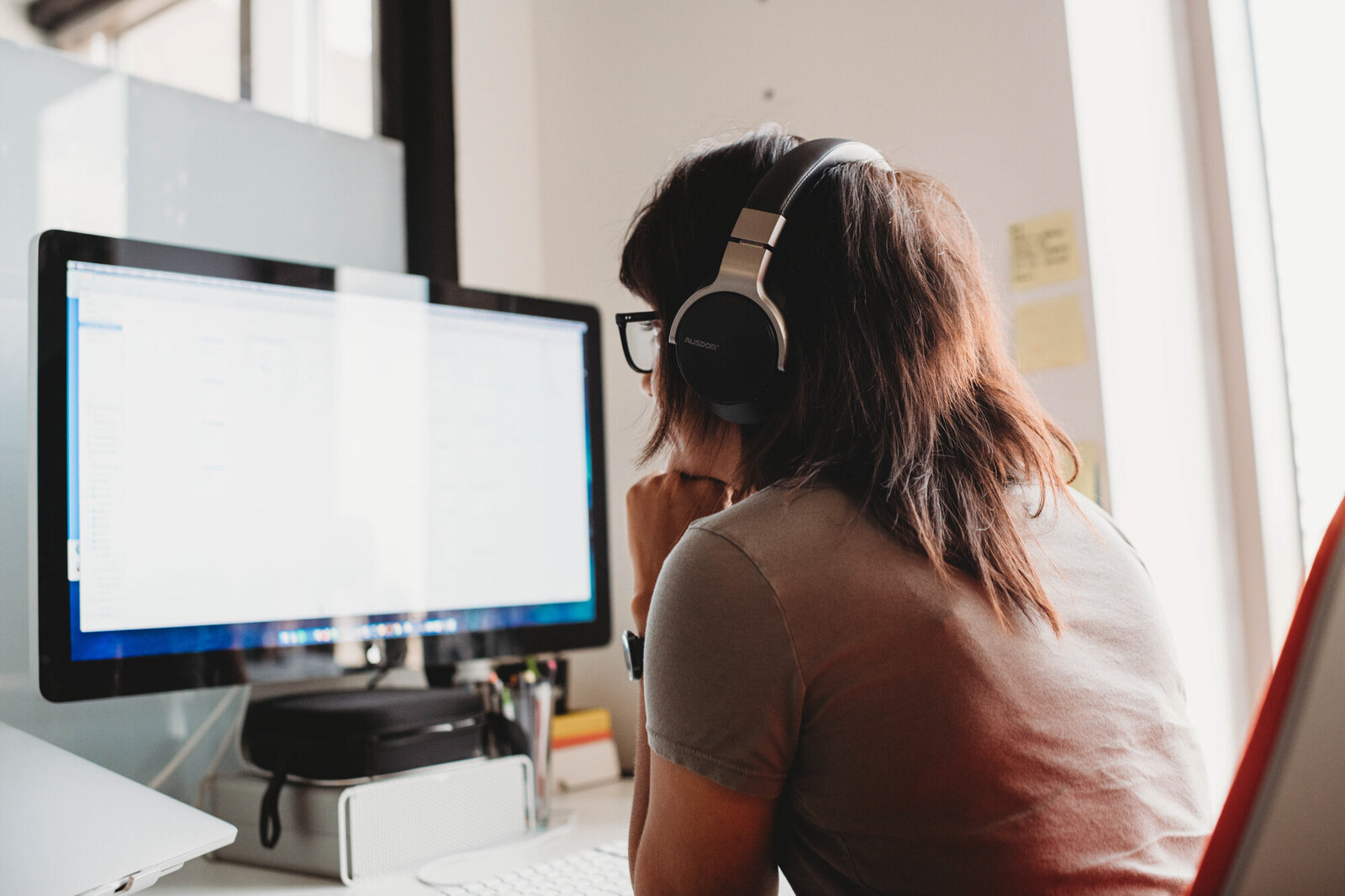 Branding Photographer,  a woman works on her Mac, she wears headphones