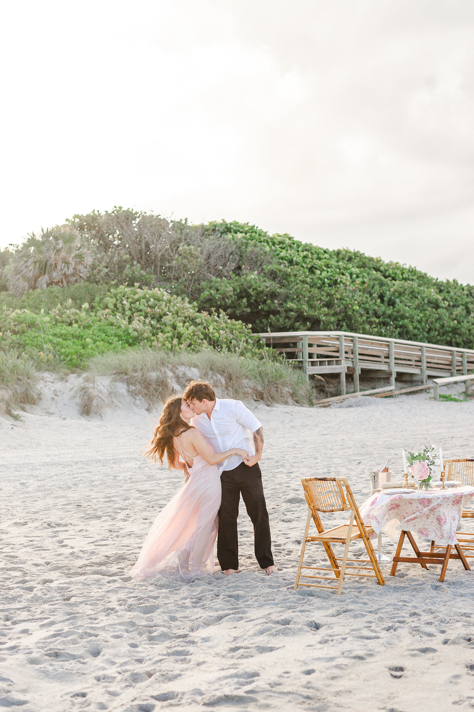 Newly engaged Orlando couple stands on beach kissing during engagement photos