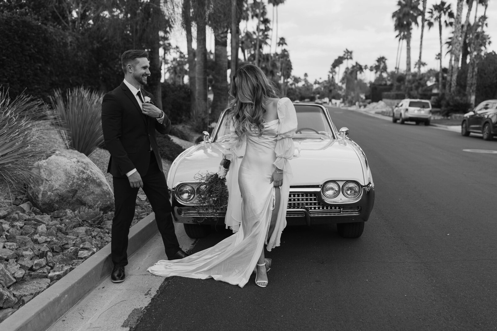 Black and white photo of bride and groom on top of desert canyon at sunset