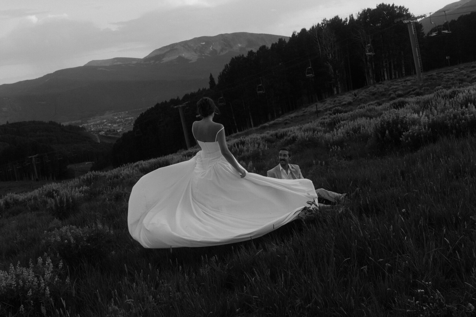 Bride spinning in her dress in front of groom on mountainside 