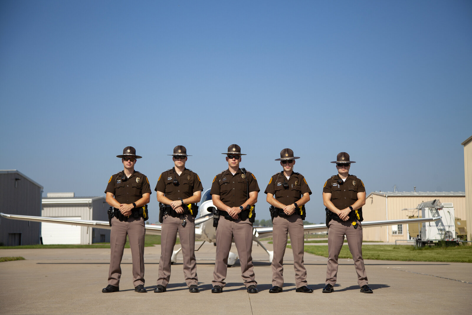 Five Iowa State Patrol pilots in uniform standing in front of a plane at the Iowa City airport.